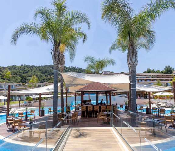 Poolside bar surrounded by palm trees and lounge chairs under sunny skies
