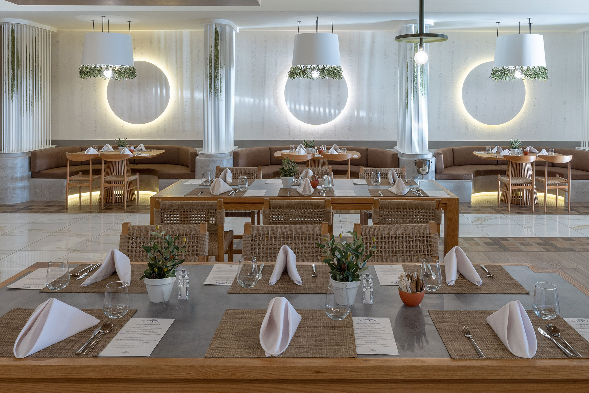 Elegant interior of Elia restaurant with wall lights, wooden tables, and earthy decor
