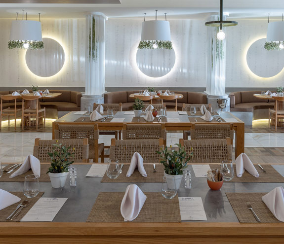 Elegant interior of Elia restaurant with wall lights, wooden tables, and earthy decor