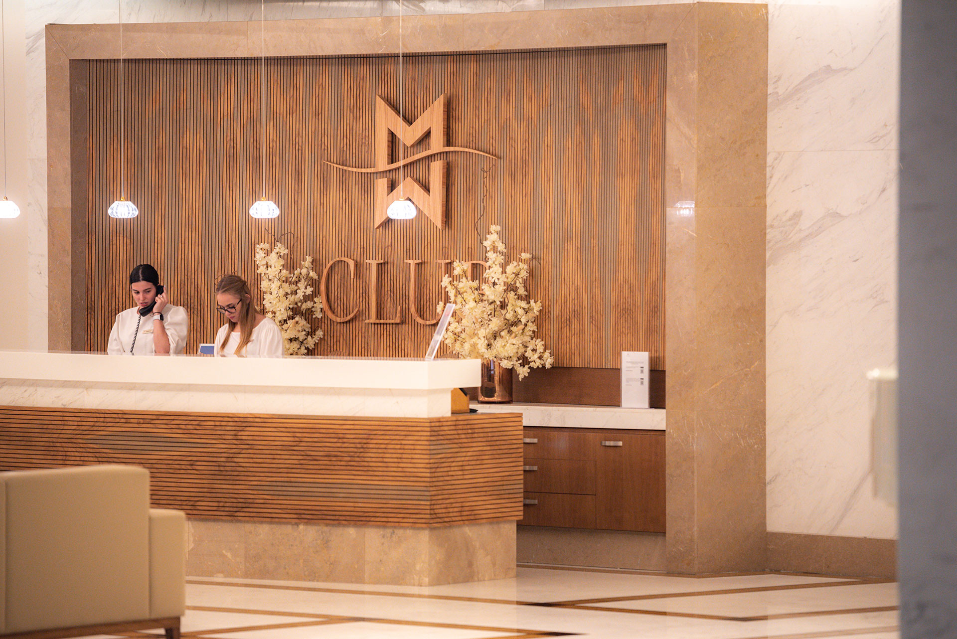 Club reception with elegant wooden wall design and attentive staff at Miraggio Thermal Spa Resort