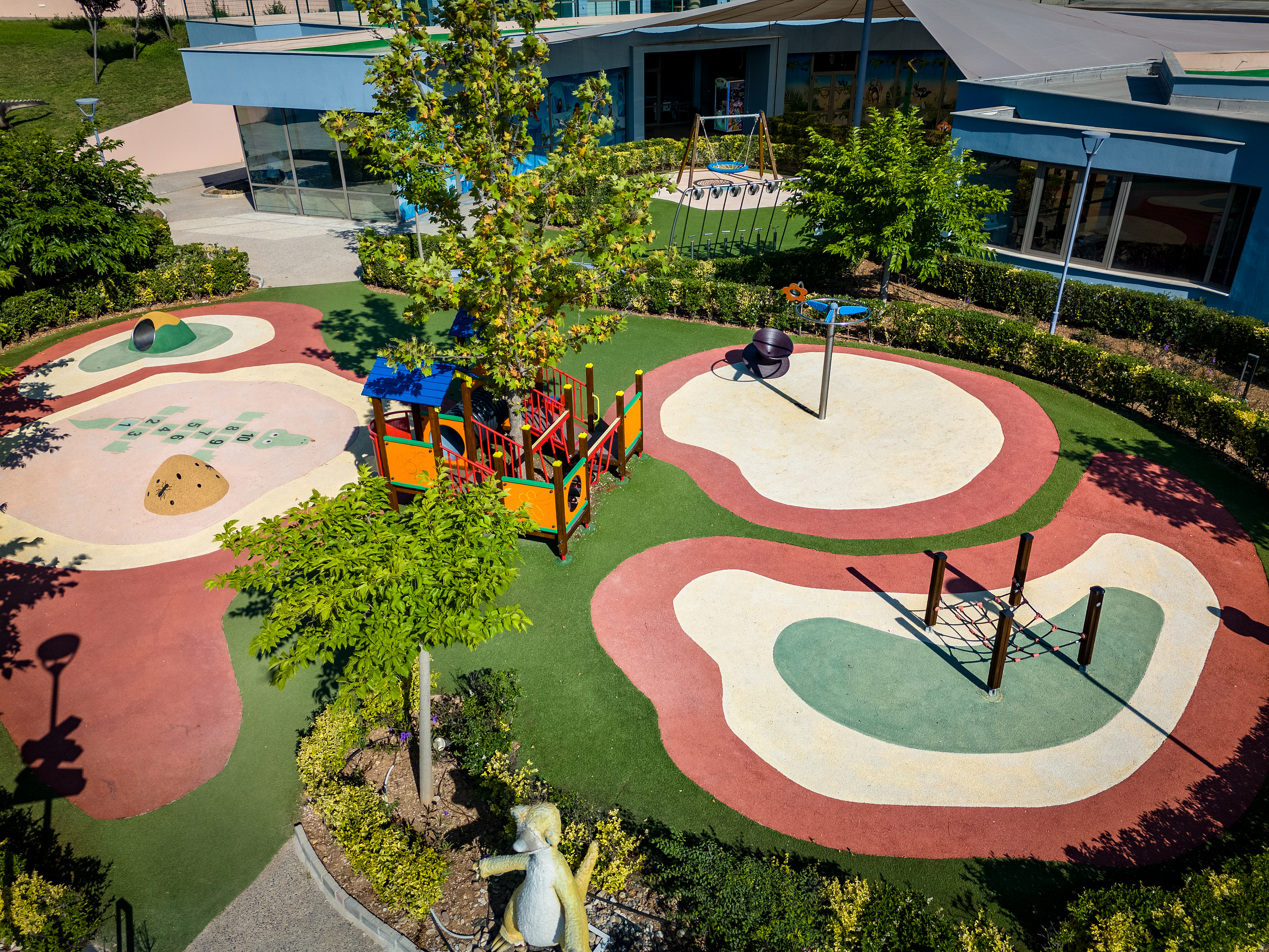 Outdoor playground with a lot of different toys in the Kids Planet surrounded by lush gardens