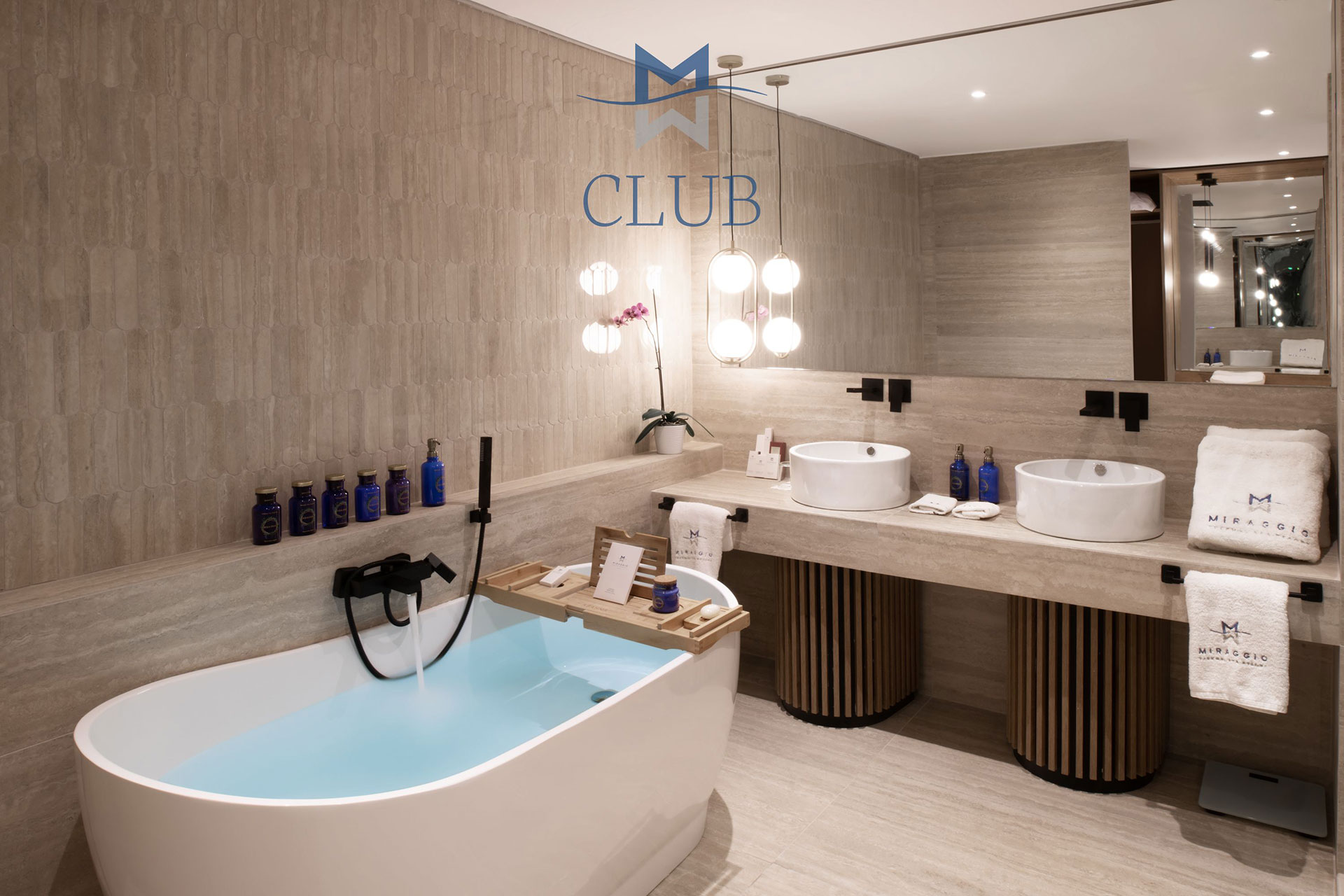 Bathroom of duplex suite with freestanding bathtub, wooden accents, and twin basins
