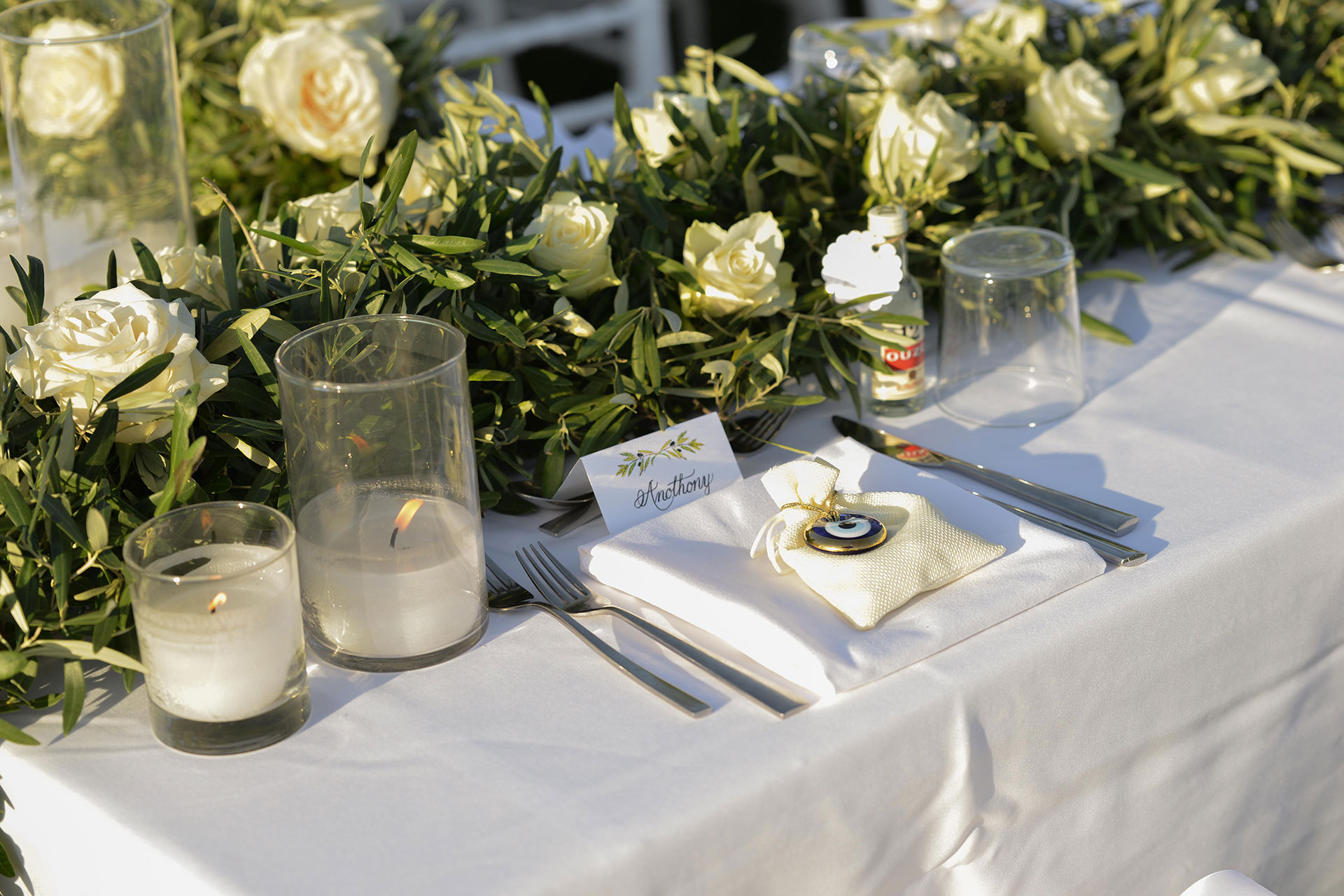 Wedding dinner table with white roses, candles, and personalized place card