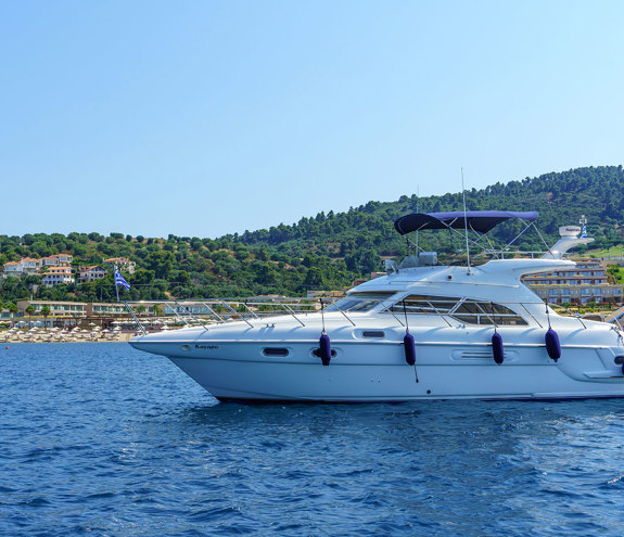 Luxury yacht sailing near the resort shoreline with clear blue sea and green hills