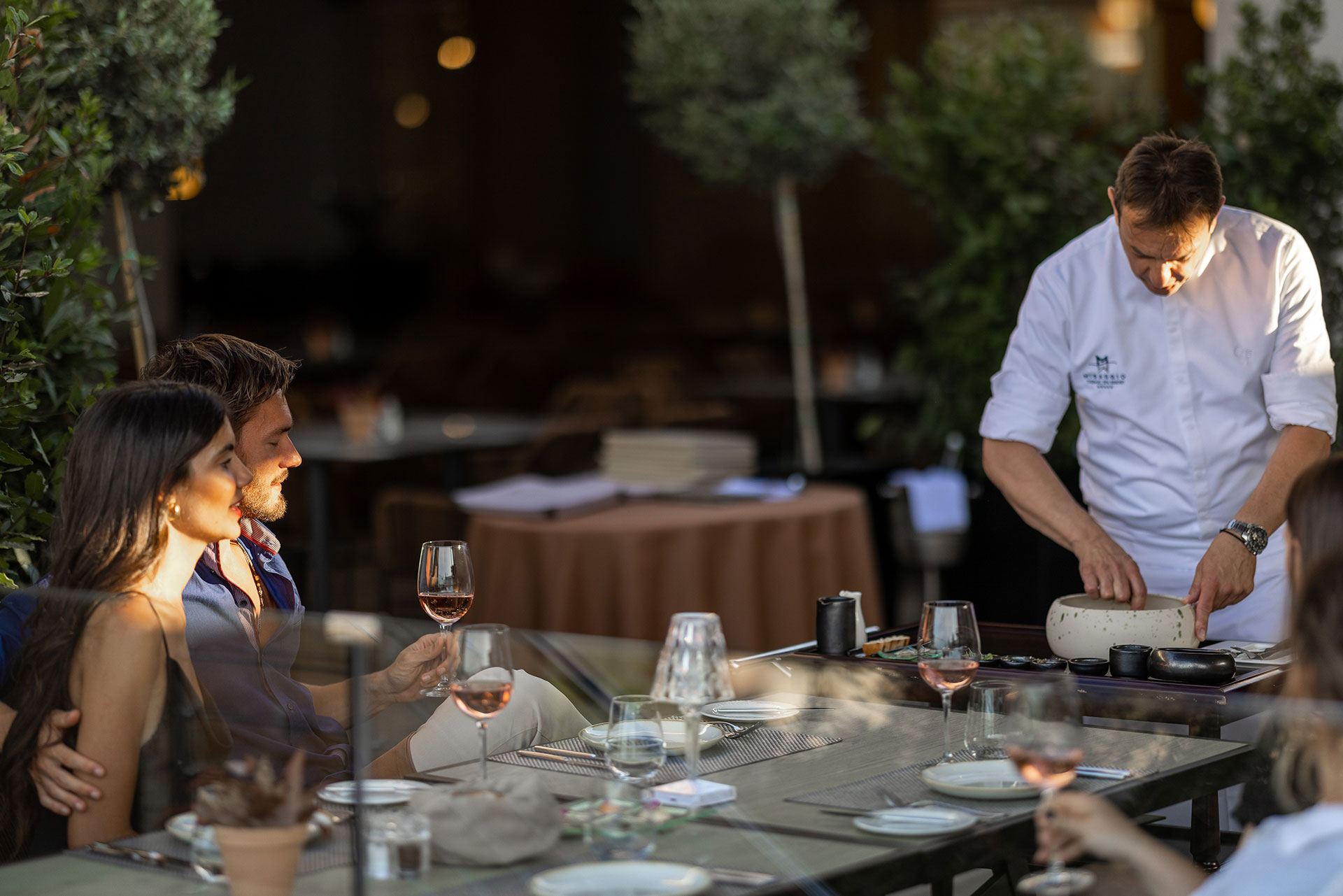Couple enjoying wine while chef prepares a live cooking presentation at Sommelier's 8 restaurant