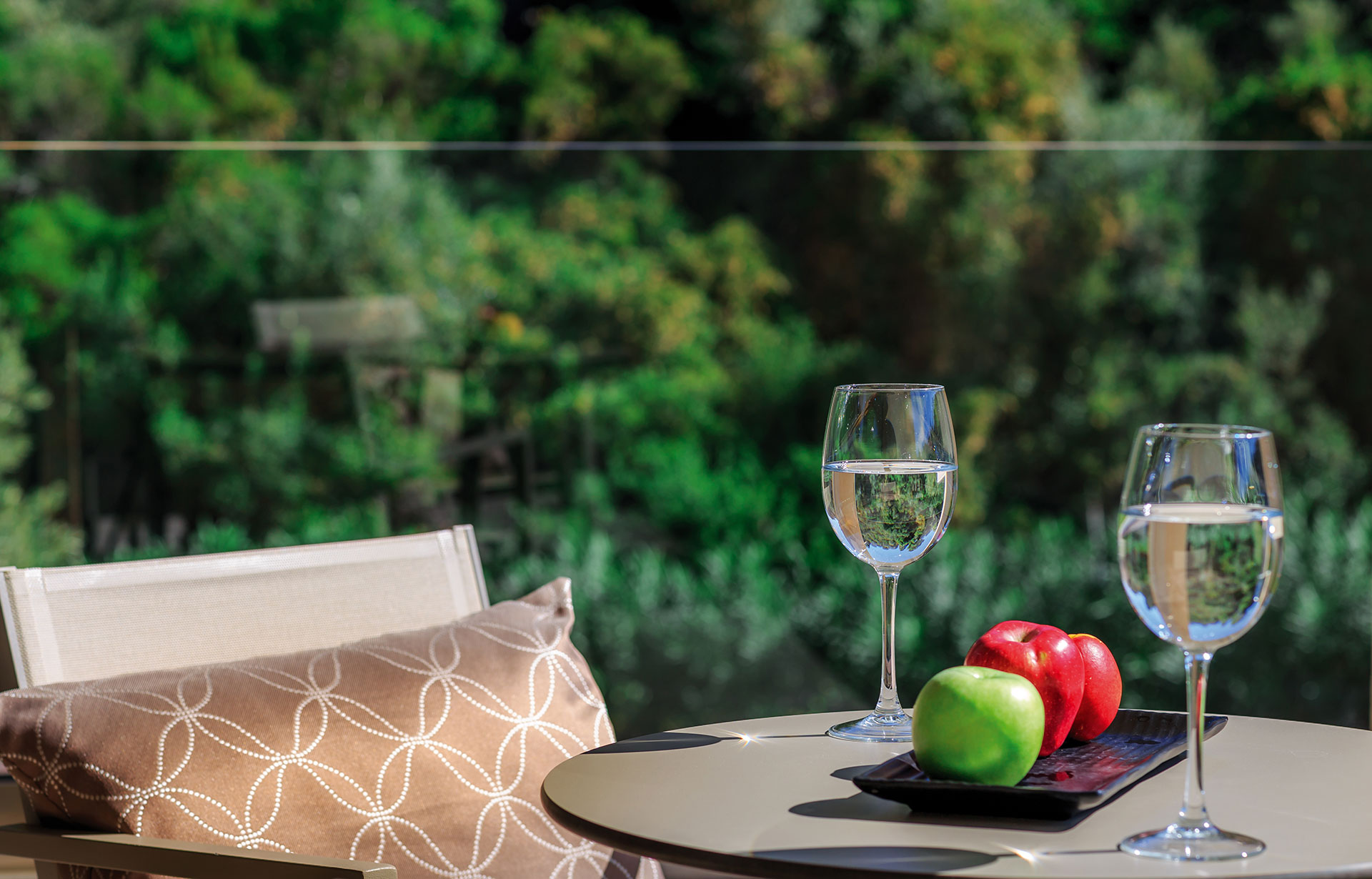Private terrace of the superior room with garden view, two glasses of water and fresh apples