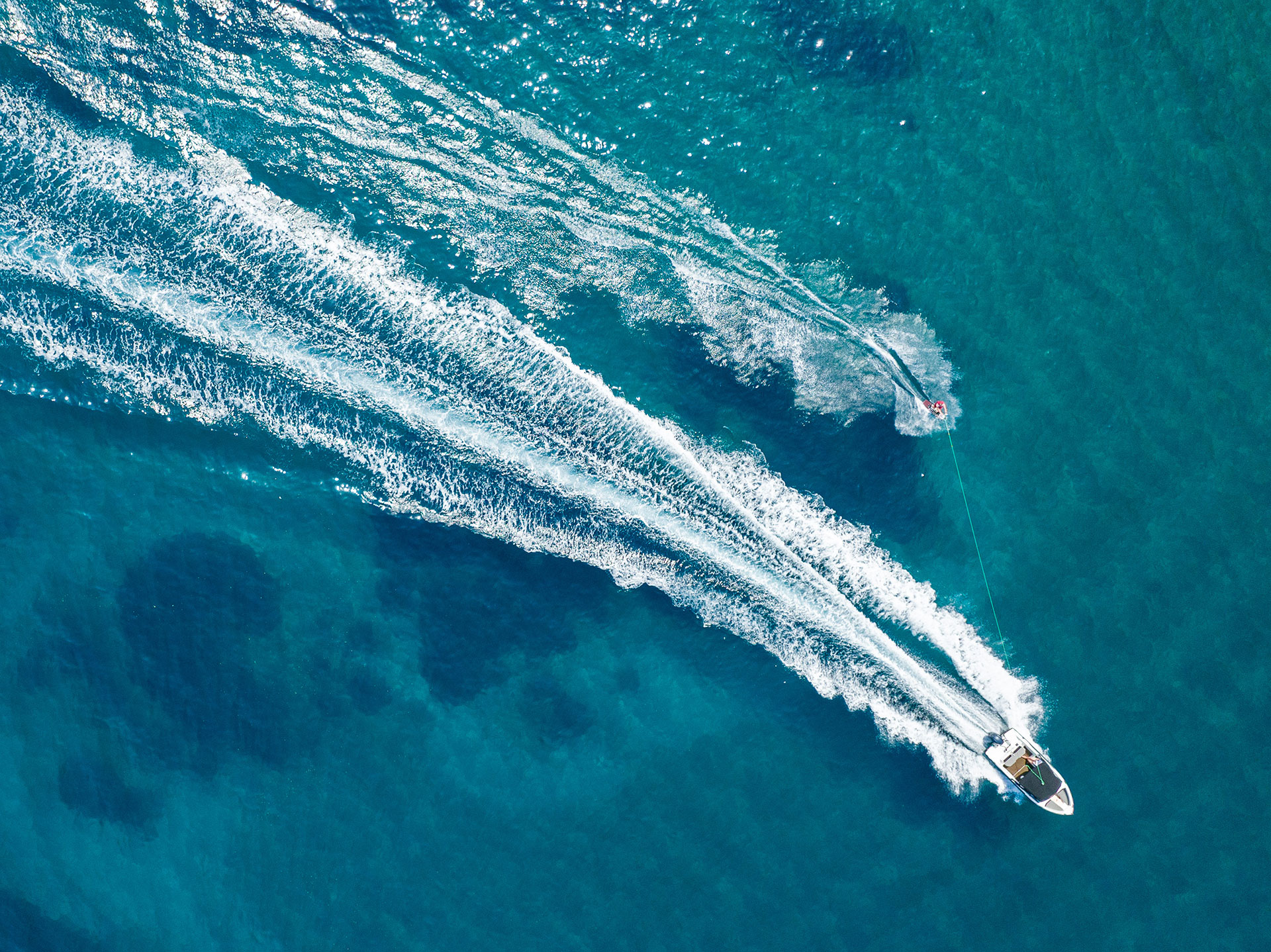Aerial view of a speedboat towing a water skier over turquoise Aegean waters