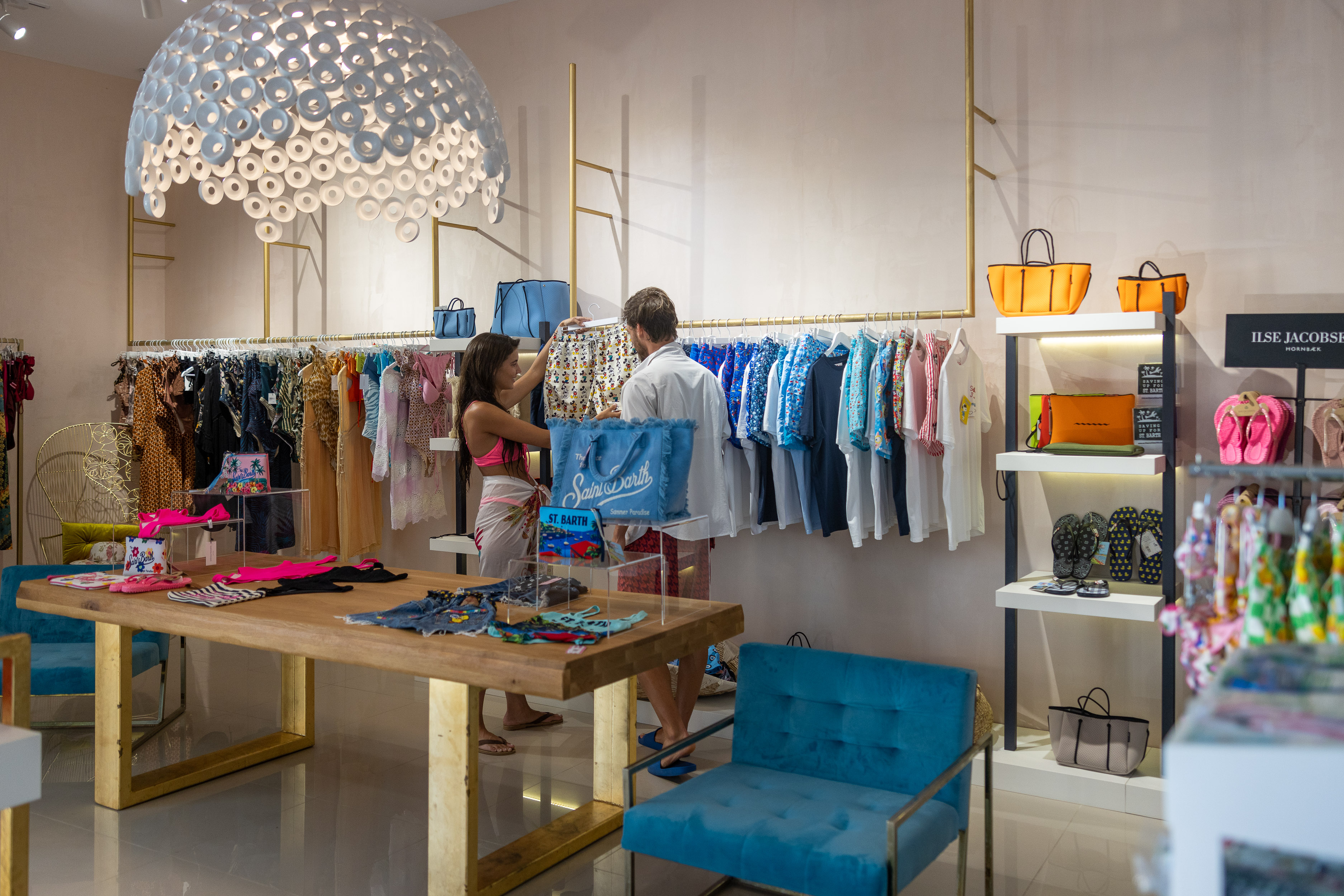 Modern boutique with stylish clothes, bags, and customers shopping inside