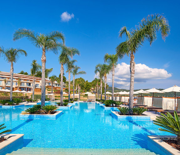 Infinity-style relax pool lined with palm trees and sun loungers under clear blue skies
