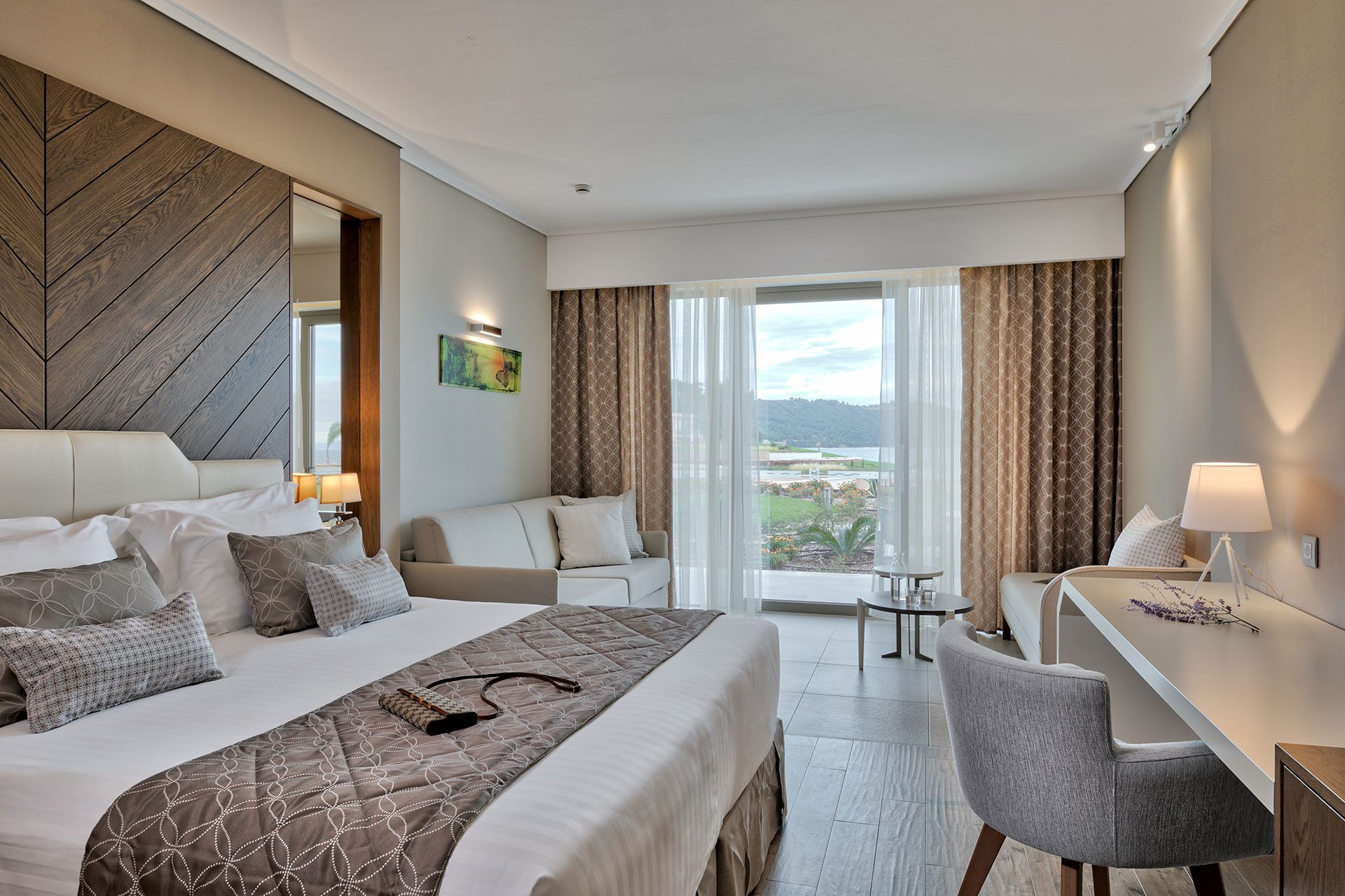 Elegant deluxe room with king bed, cozy seating area and terrace overlooking the resort gardens