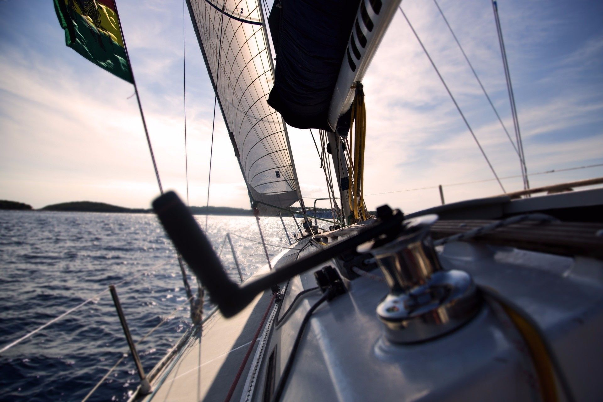 View from a sailing yacht gliding over the Aegean Sea with open sails under the afternoon sun
