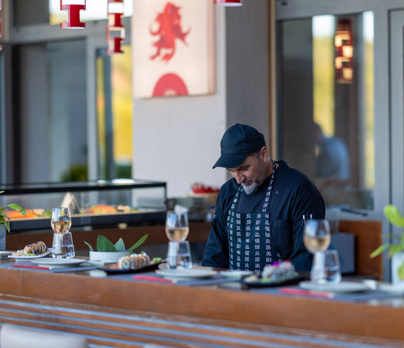 Sushi chef preparing fresh rolls behind the counter at the Lobby Sushi Bar