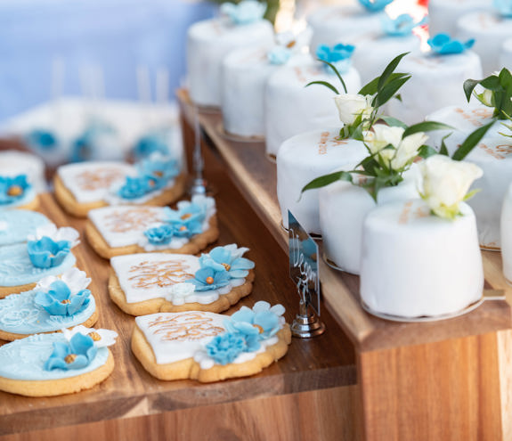 Elegant wedding desserts with white fondant and blue floral decorations