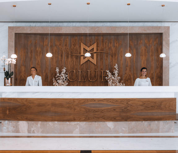 Modern reception area with elegant wooden design and welcoming staff at The Club lobby