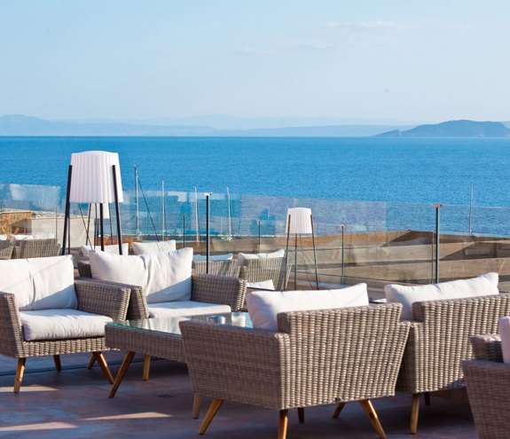 Outdoor seating area beside the glass balcony railing with panoramic sea view