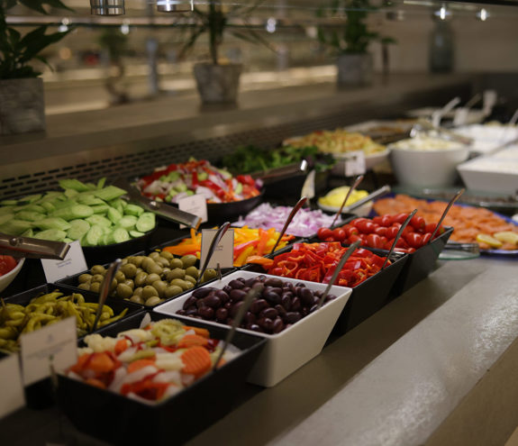 Close up to salad buffet in Kritamo restaurant featuring cucumbers, olives, tomatoes and other freshly cut vegetables