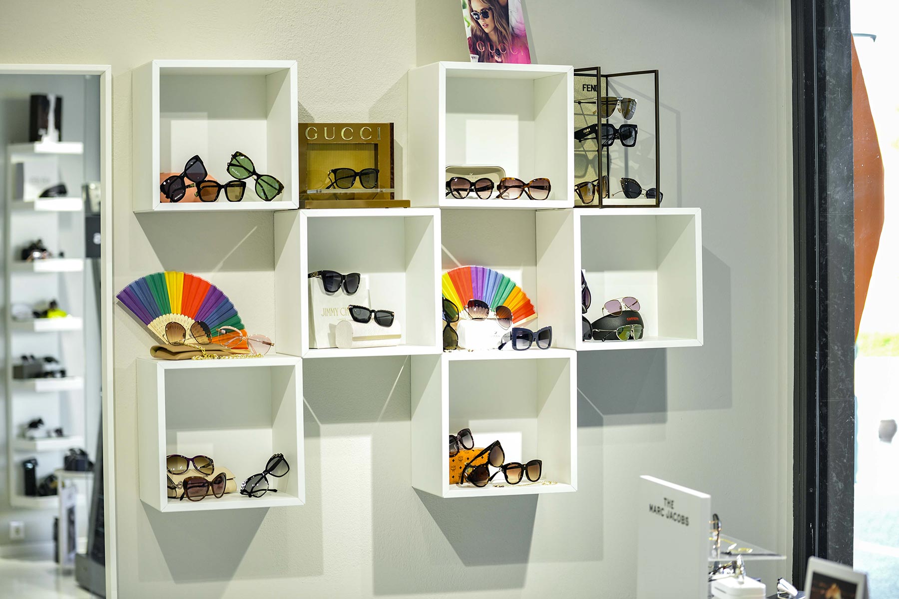 Wall display of designer sunglasses and colorful fans inside luxury boutique