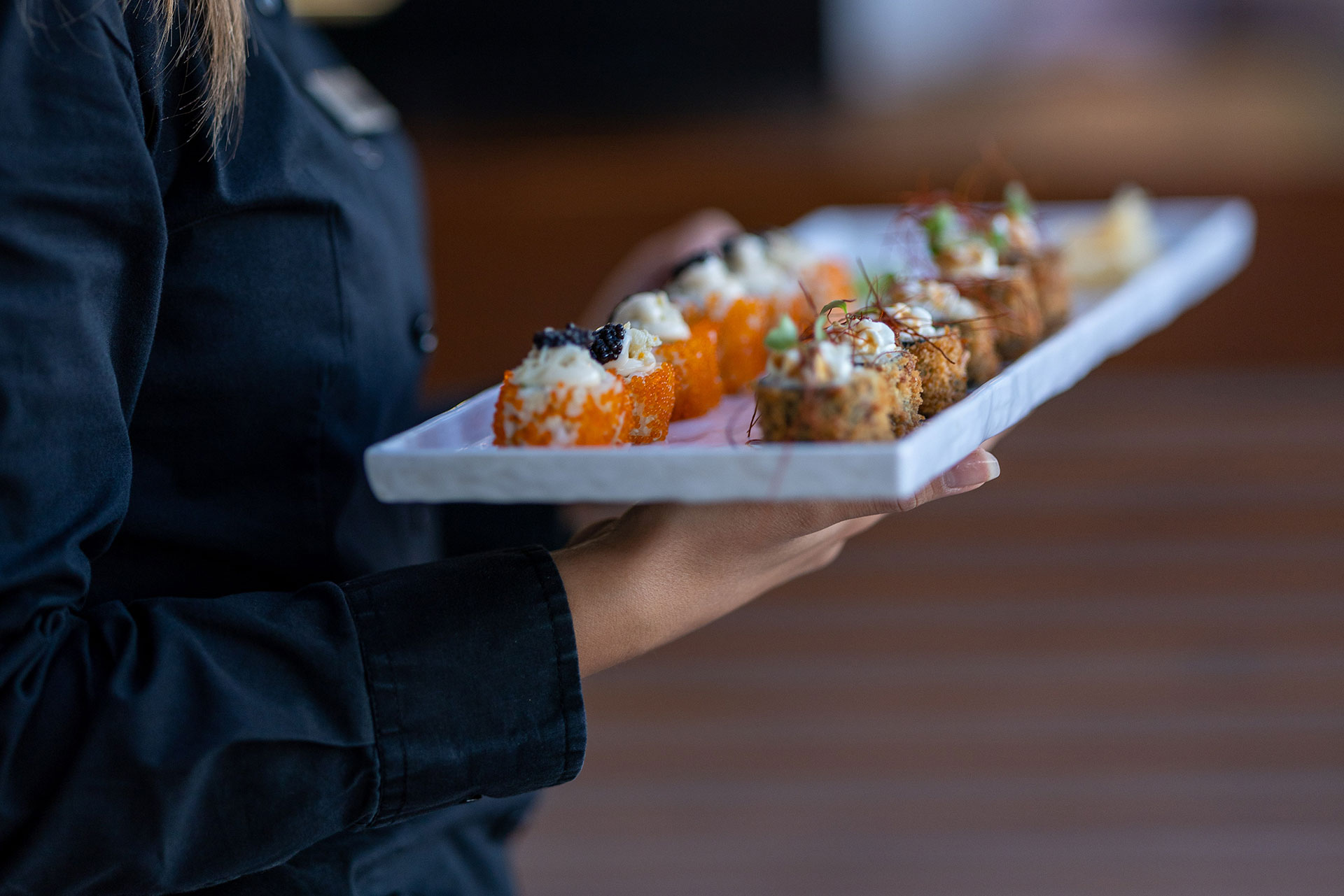 Waitress serving assorted sushi rolls with elegant presentation 
