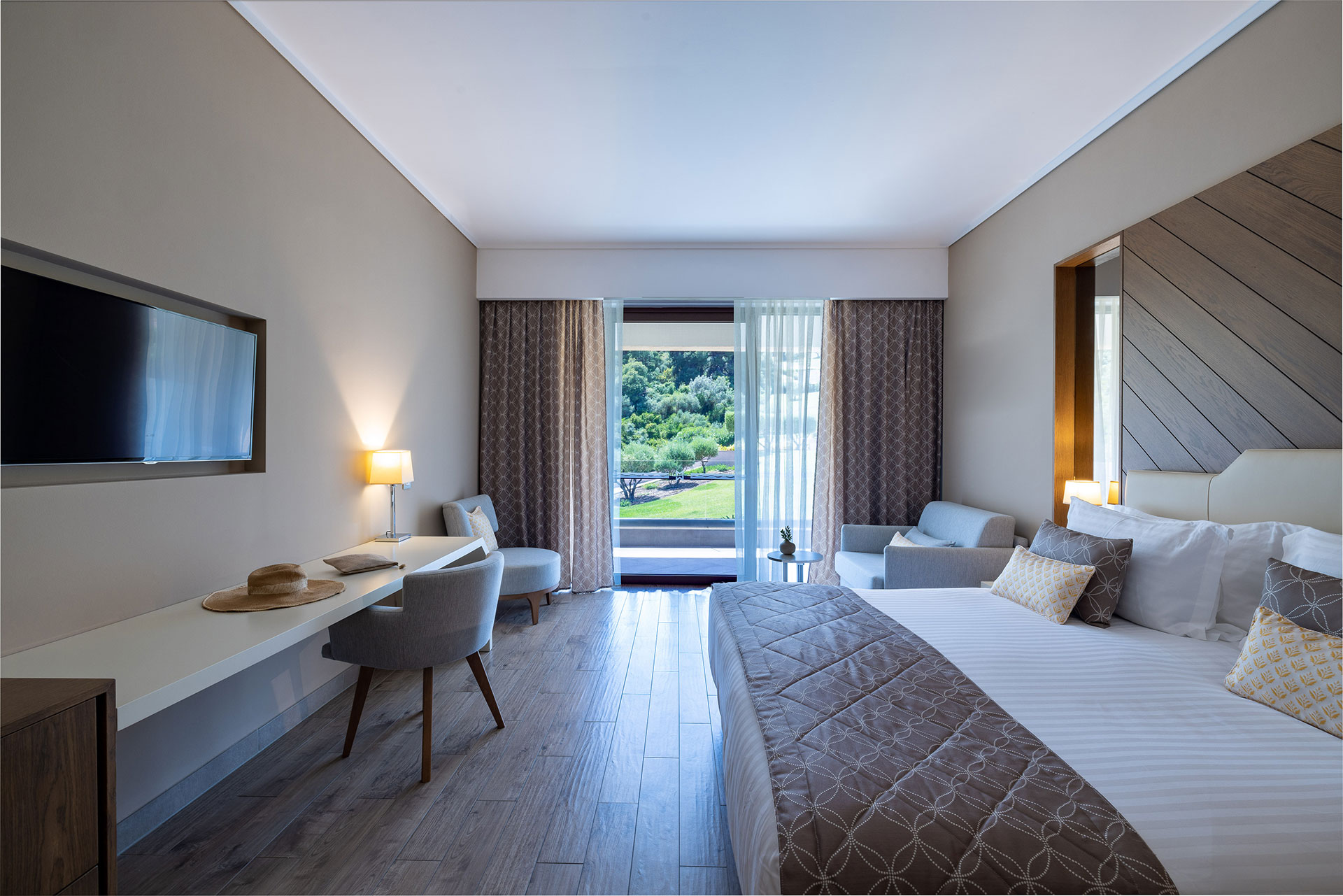 Bright room with king bed, modern decor and private terrace overlooking lush gardens