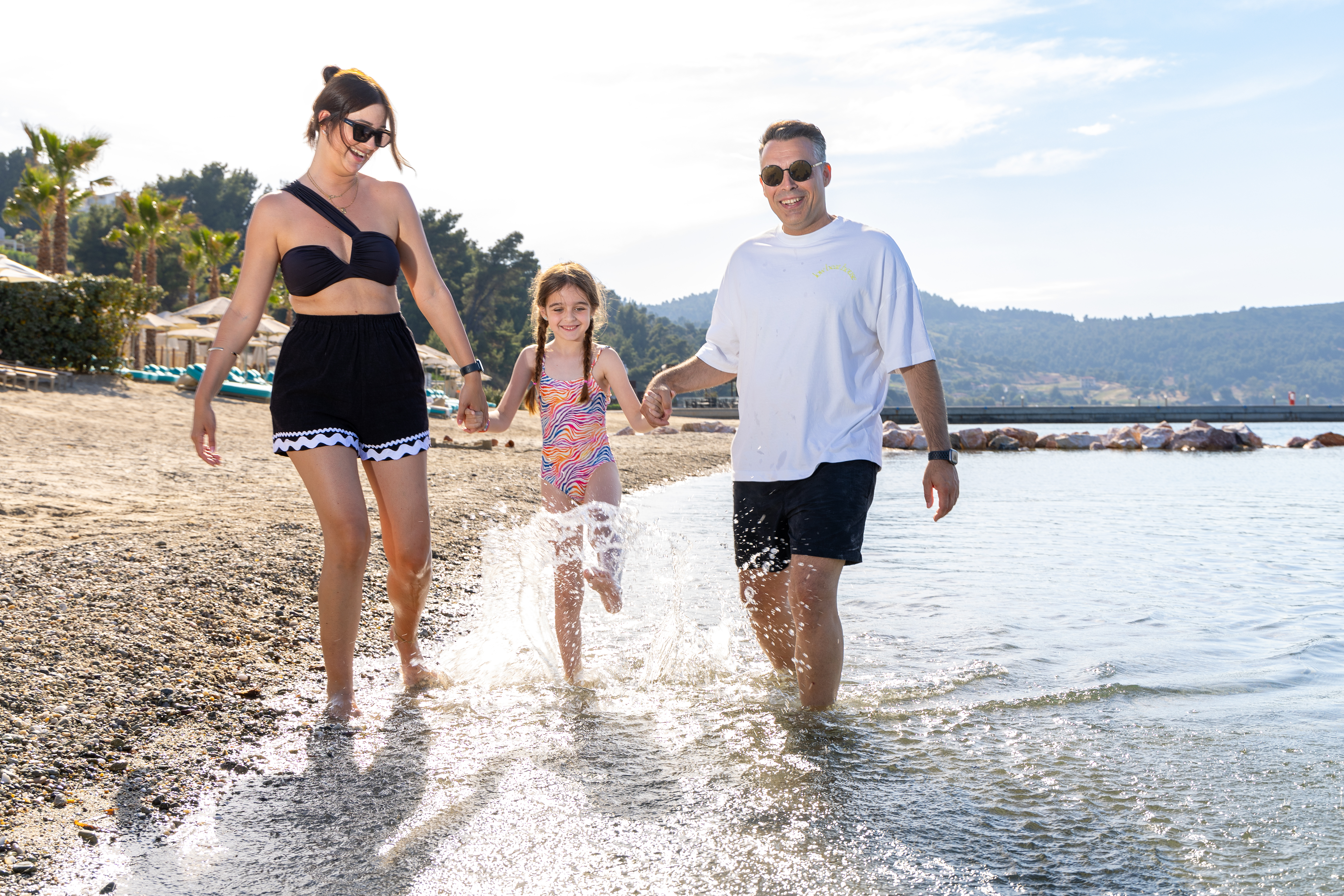 Happy family walking by the sea and splashing water on the beach