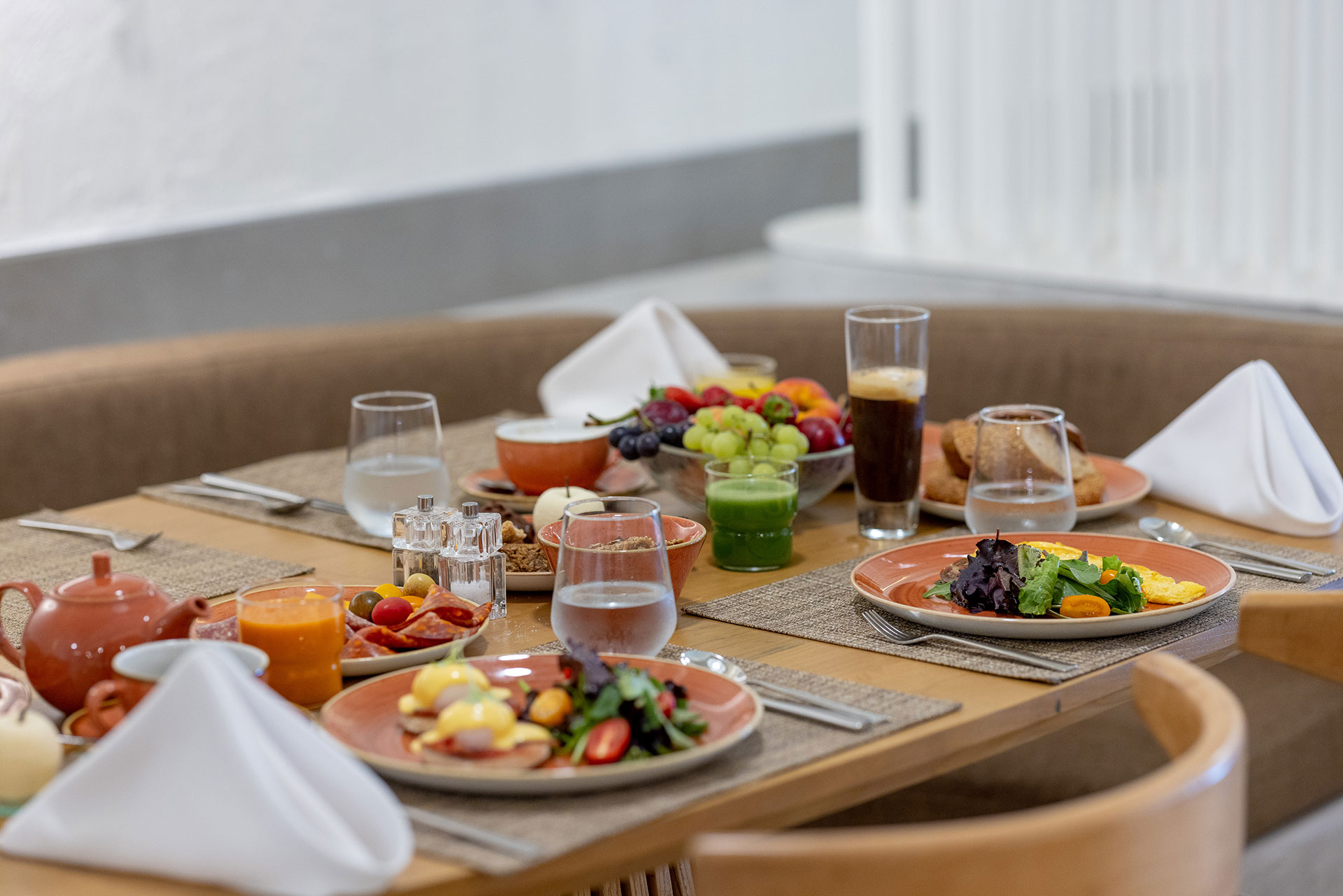 Elegant breakfast setup with omelets, Eggs Benedict, fruits, and fresh juices on a cozy table
