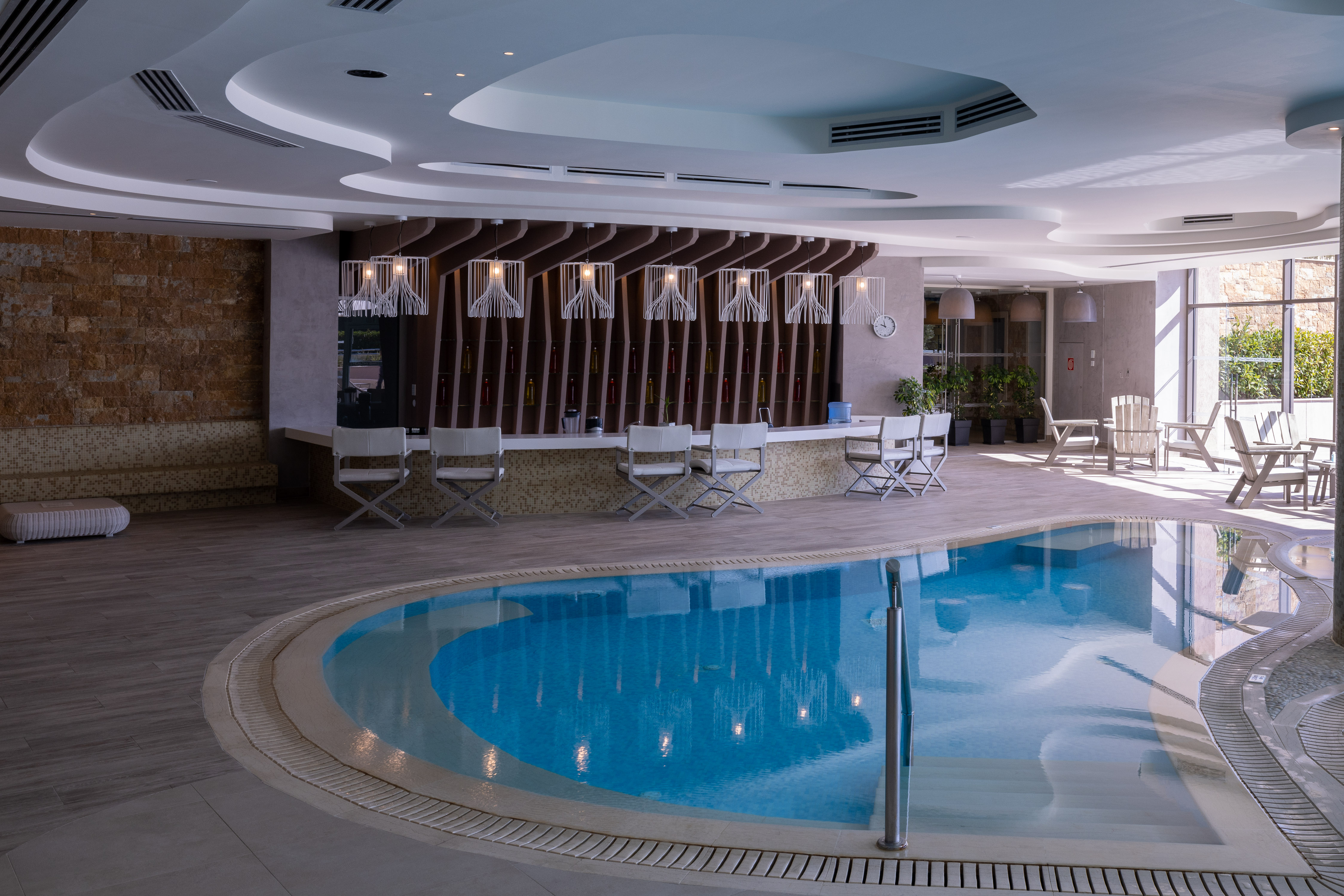 Modern indoor pool with elegant bar area and relaxing lounge chairs