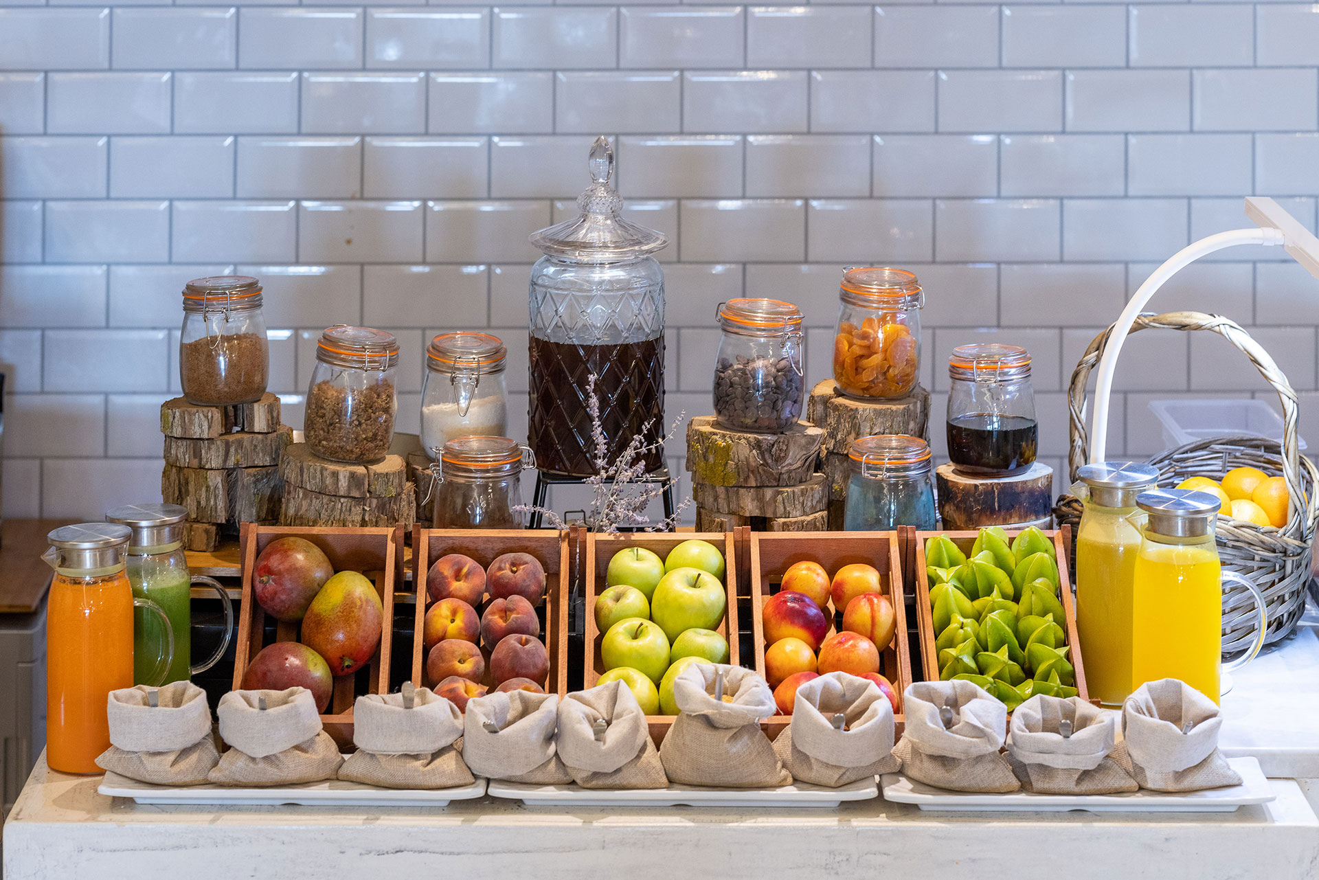 Breakfast juice and fruit display with apples, peaches, dried fruits, and cereals in glass jars