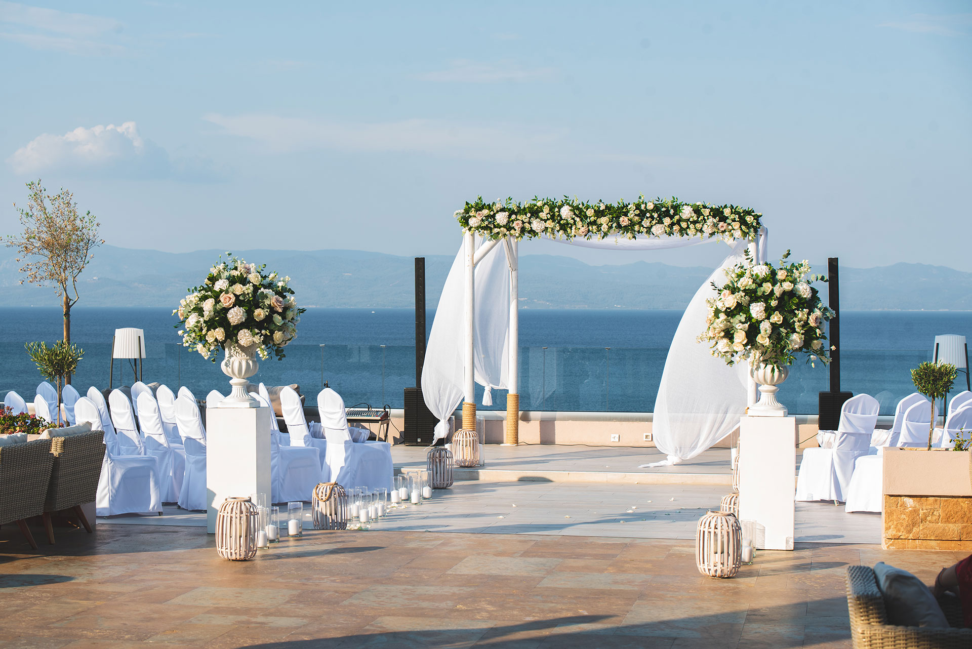 Romantic outdoor wedding venue with floral arch and sea view under clear skies