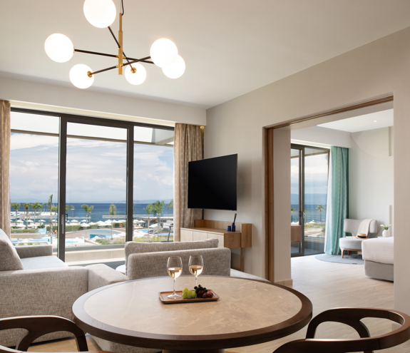 Elegant living area of the suite with modern furnishing and glass doors overlooking the resort and the sea