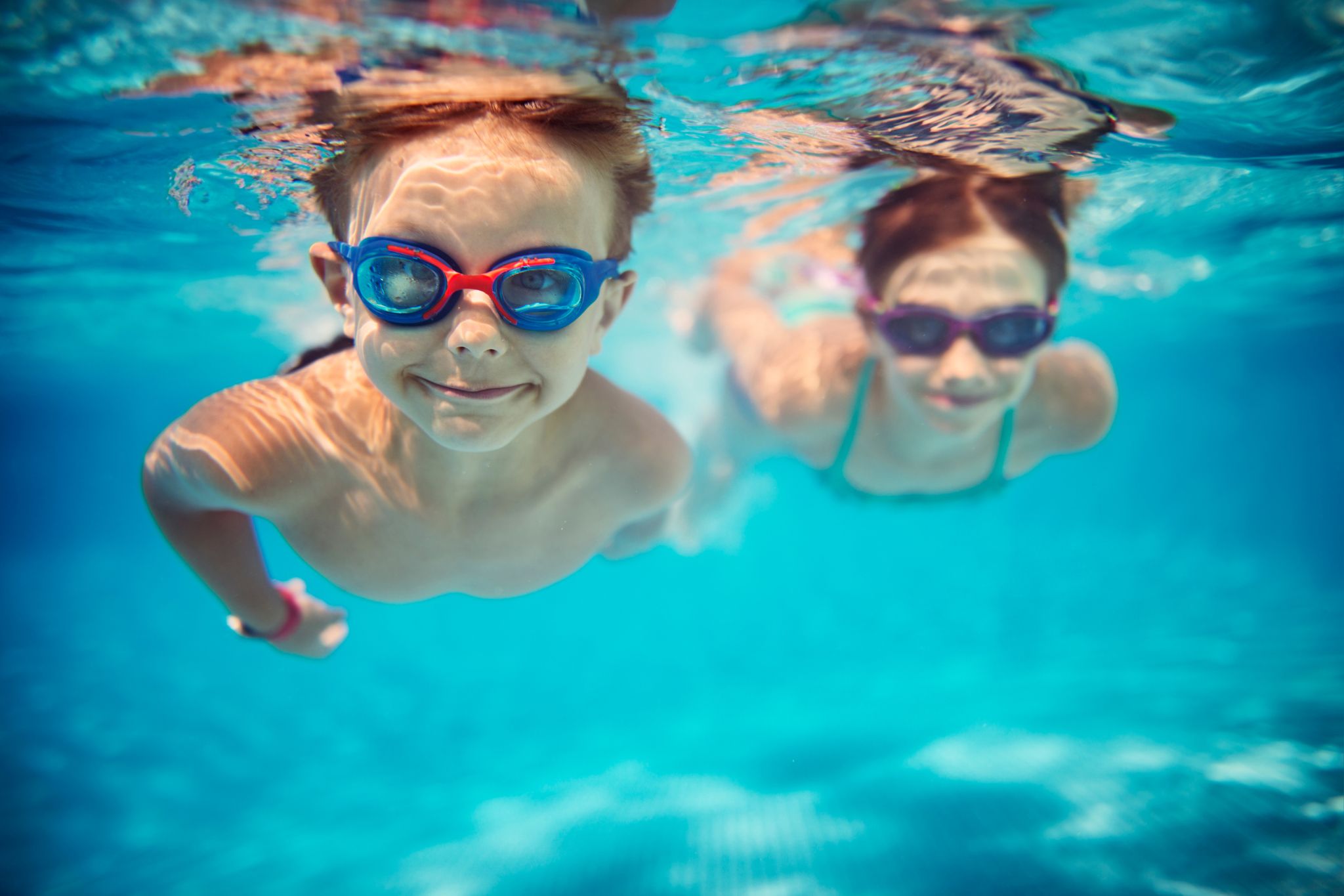 Two children wearing swim masks enjoying a swimming lesson in the sea