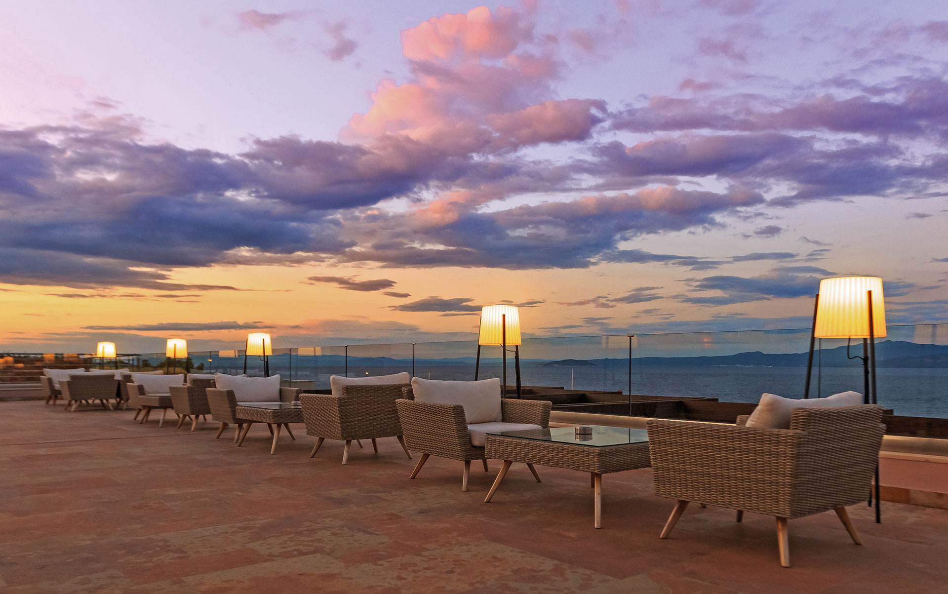 Romantic terrace setup under a purple sunset sky overlooking the calm sea