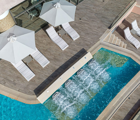 Spa terrace with bubbling hydro loungers and white sunbeds under umbrellas
