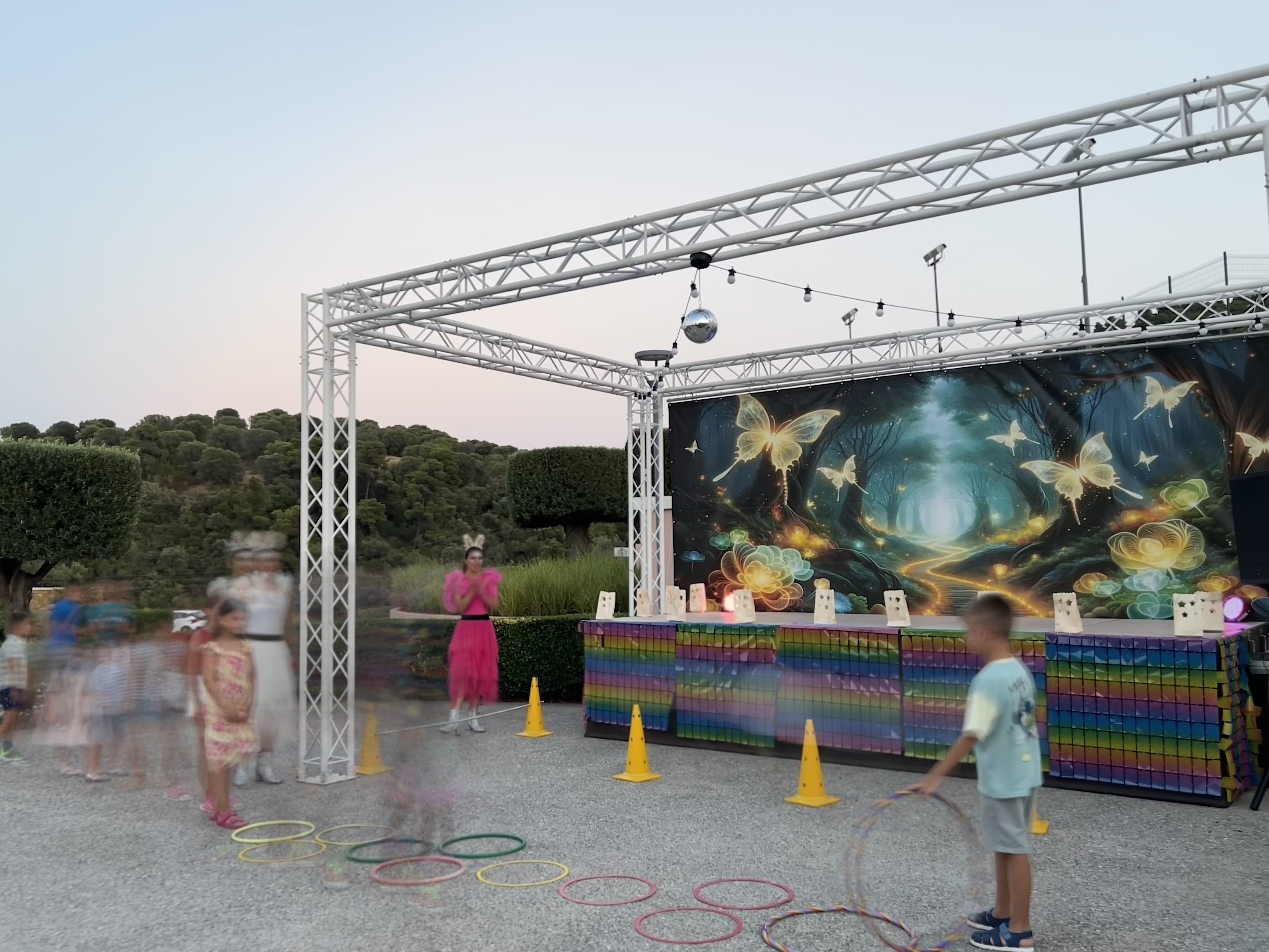 Children playing outdoor games during an early evening kids' activity show with fantasy-themed stage