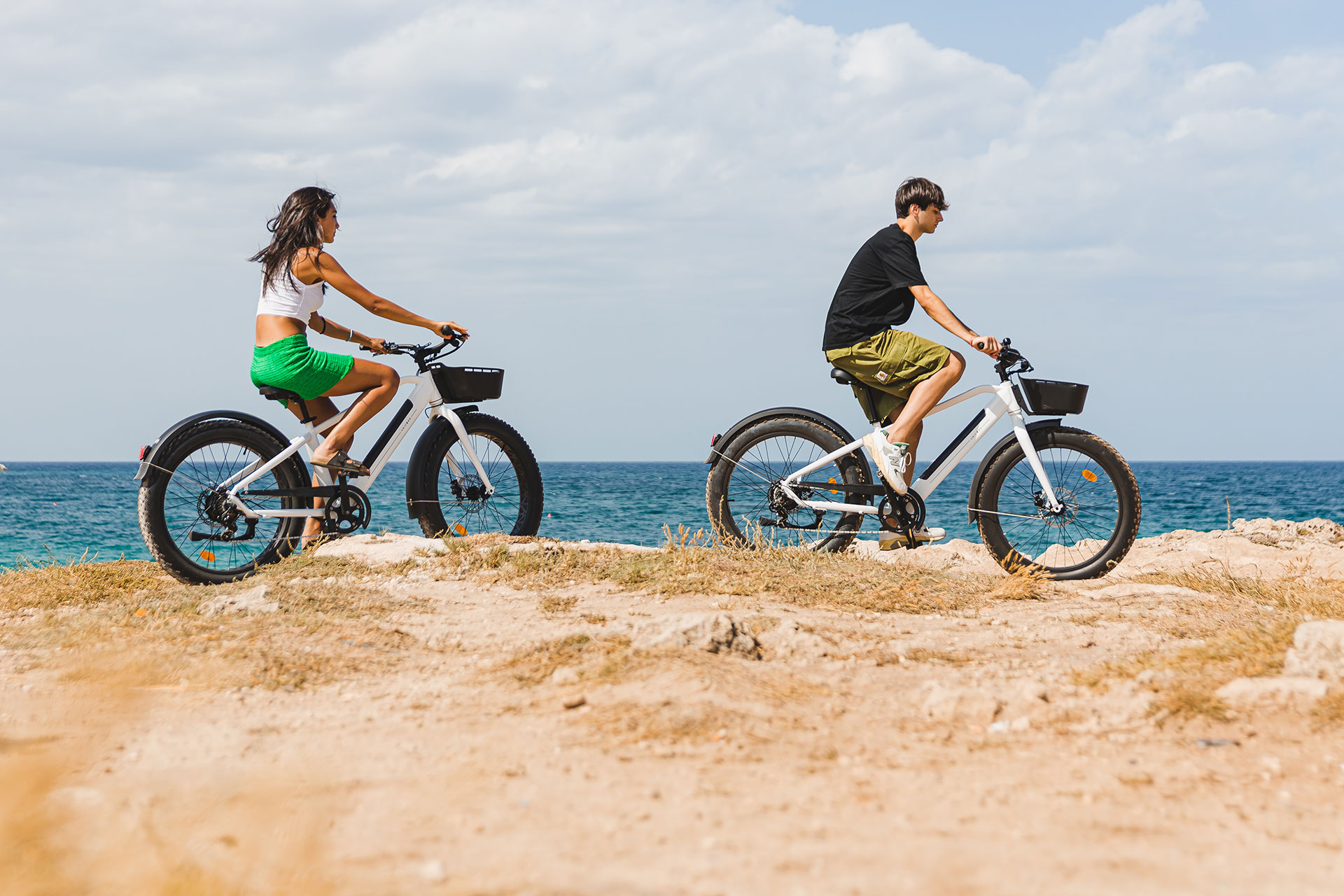 Couple riding electric bicycles along the seaside trail with scenic views