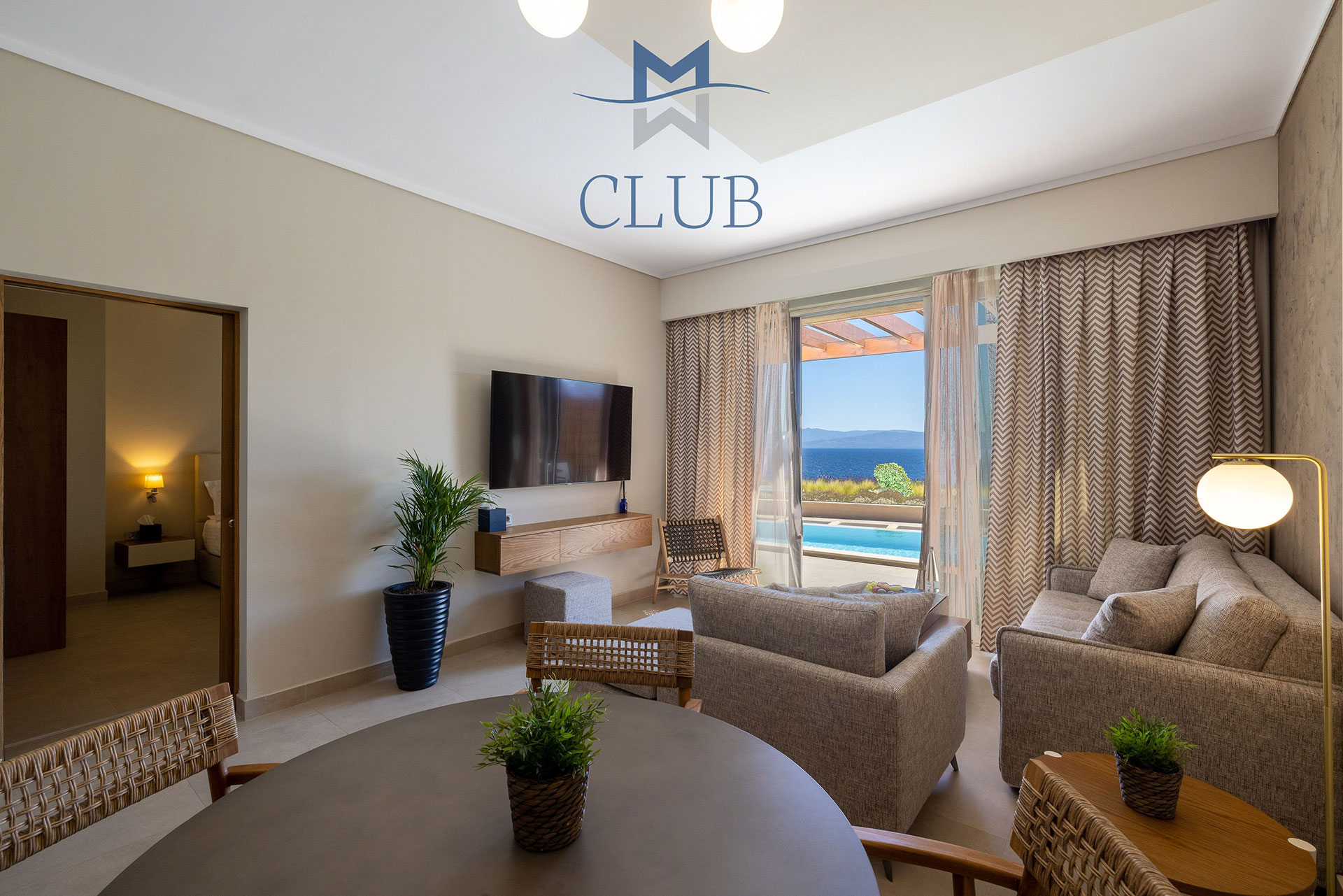 Spacious living room of suite, with dining area, and cozy seating with wall mounted TV