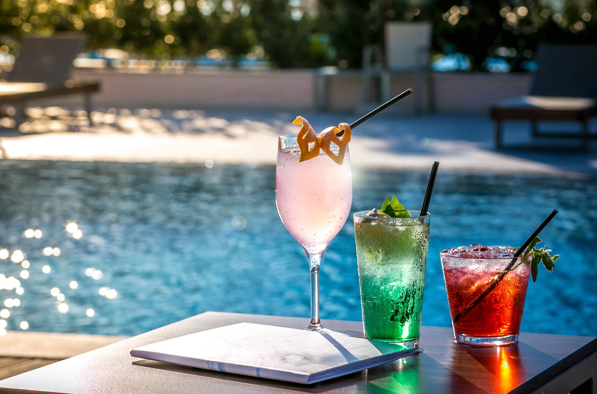 Colorful refreshing cocktails served on the bar counter of Oasis Pool Bar with the pool in the background