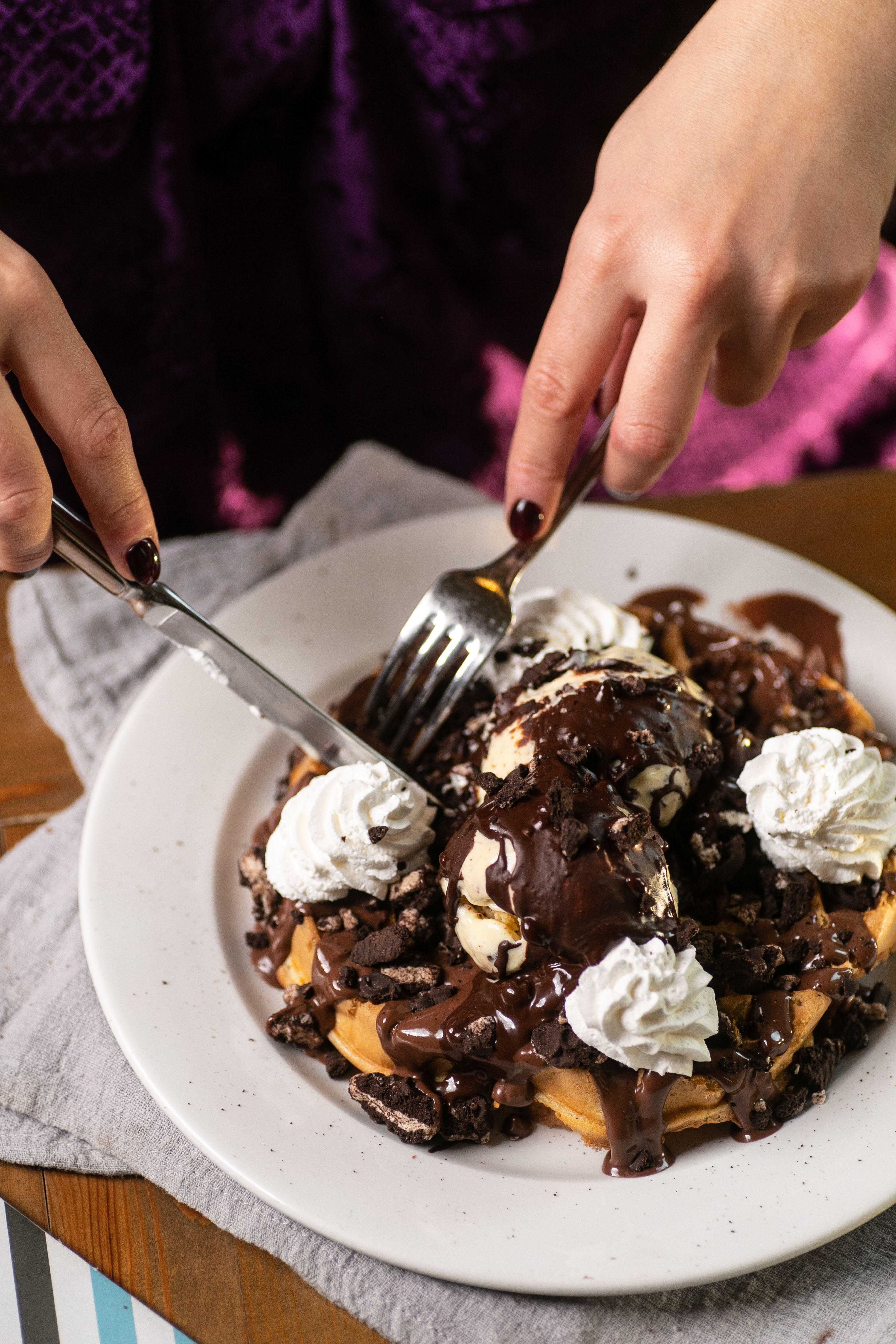 Delicious fregio waffle with vanilla ice cream, chocolate sauce, whipped cream, and cookie crumble