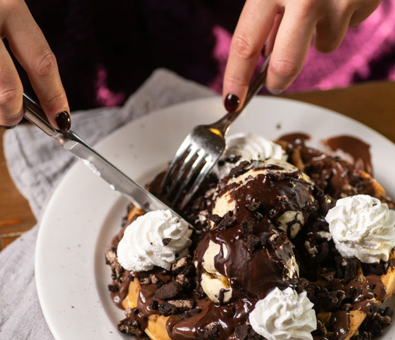 Delicious fregio waffle with vanilla ice cream, chocolate sauce, whipped cream, and cookie crumble