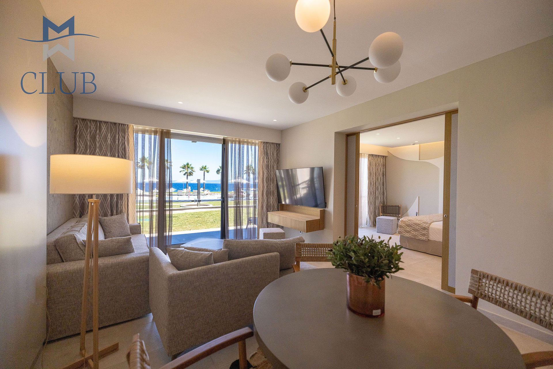 Spacious and elegant suite with seating area, dining table, and glass doors with pool view