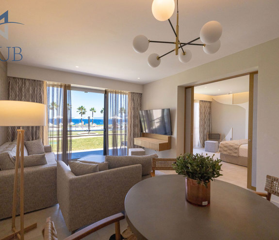 Spacious and elegant suite with seating area, dining table, and glass doors with pool view