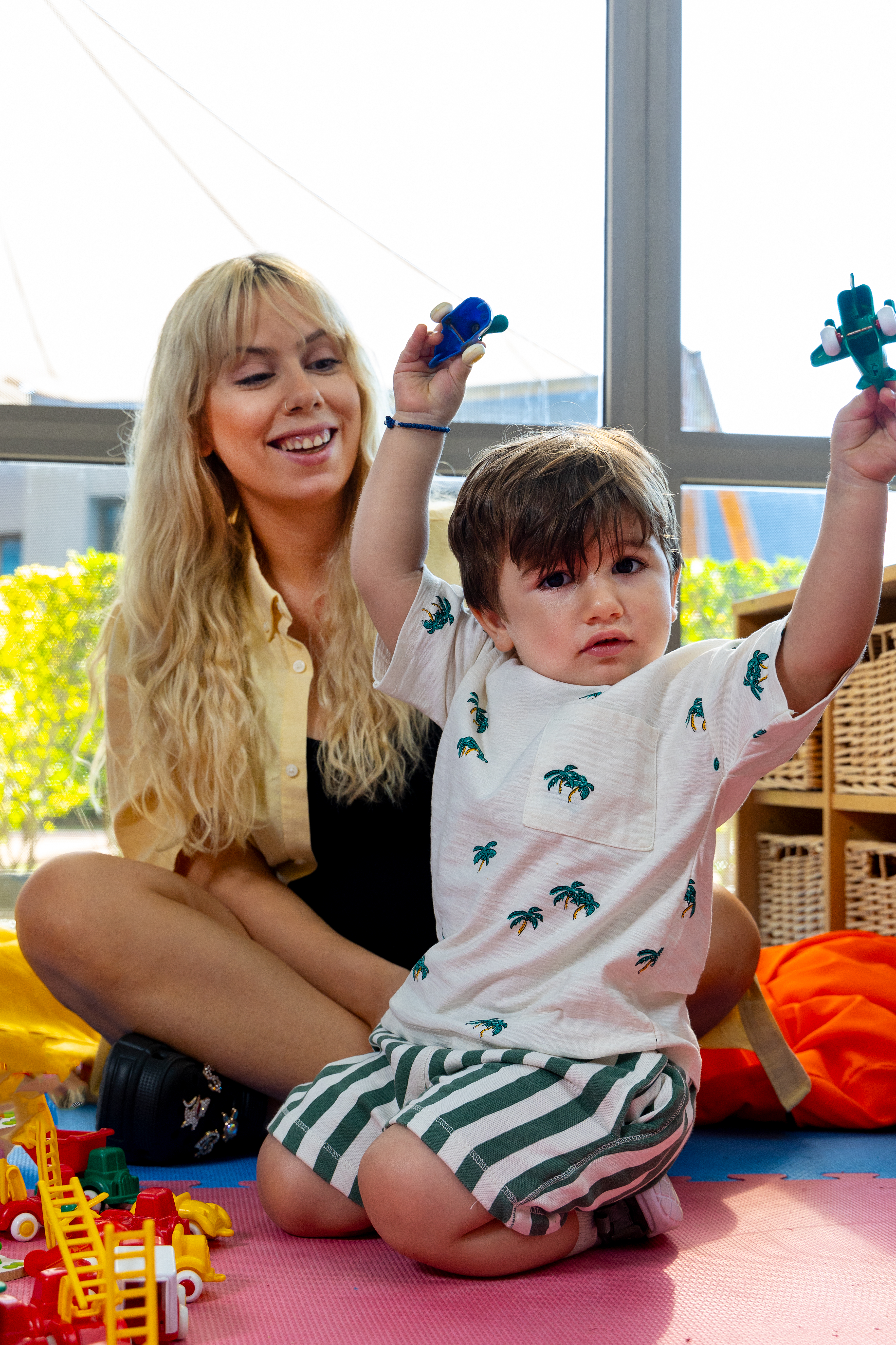 Happy toddler enjoy playing with toys near its parents in the indoor playground of Kids Planet
