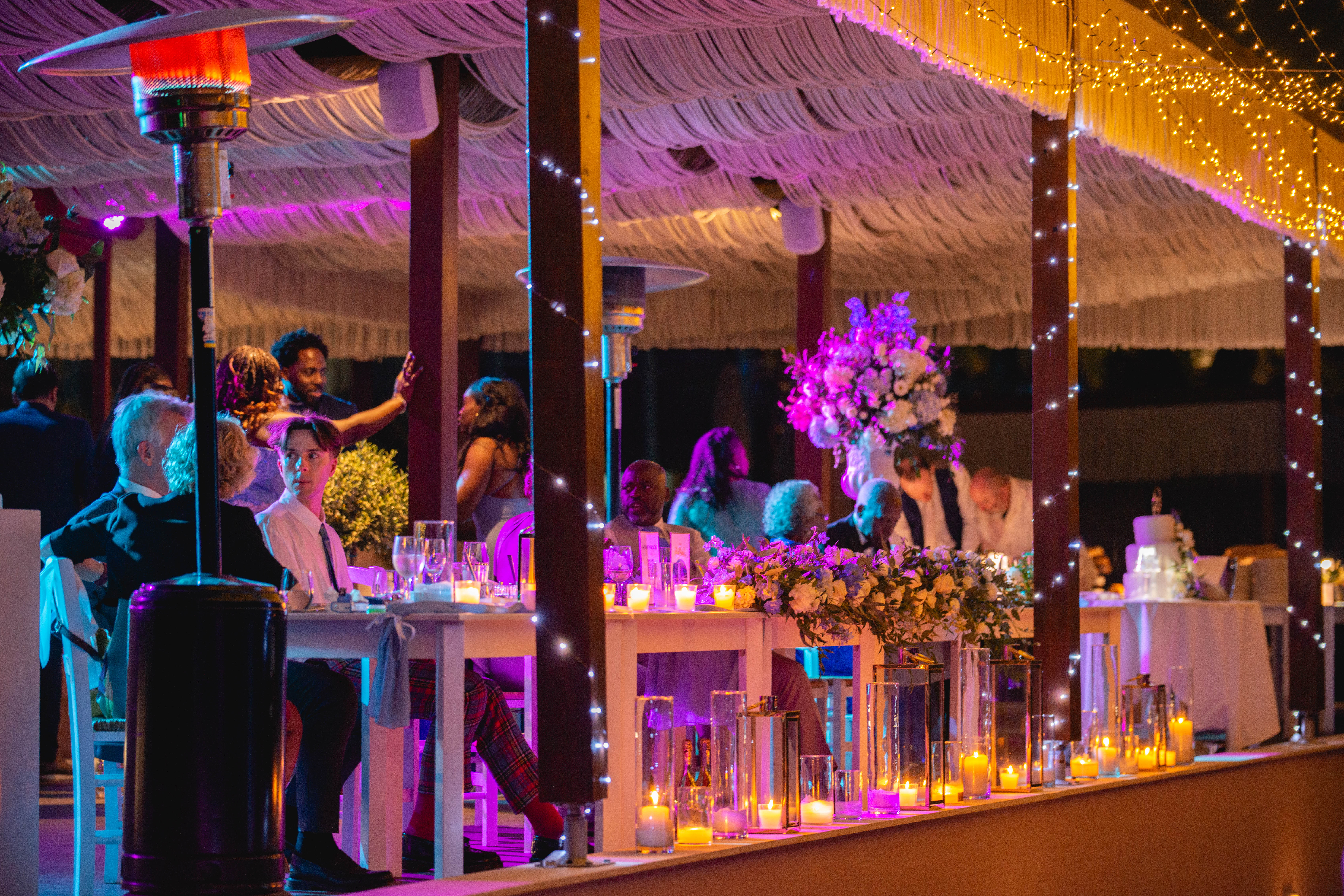 Romantic beachfront wedding dinner with candlelit tables and string lights