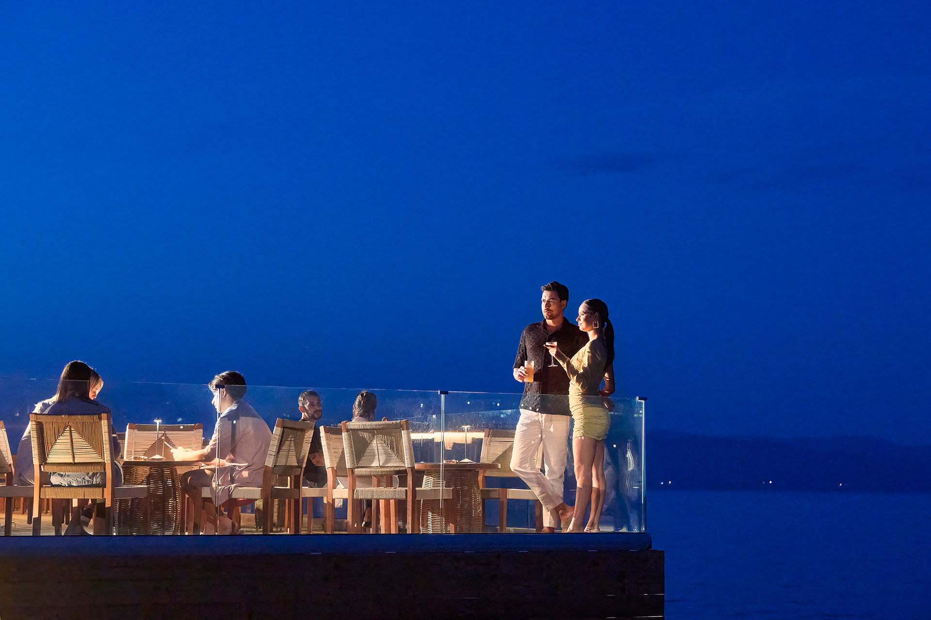 Couple enjoying a conversation at the corner of the dock under night lights