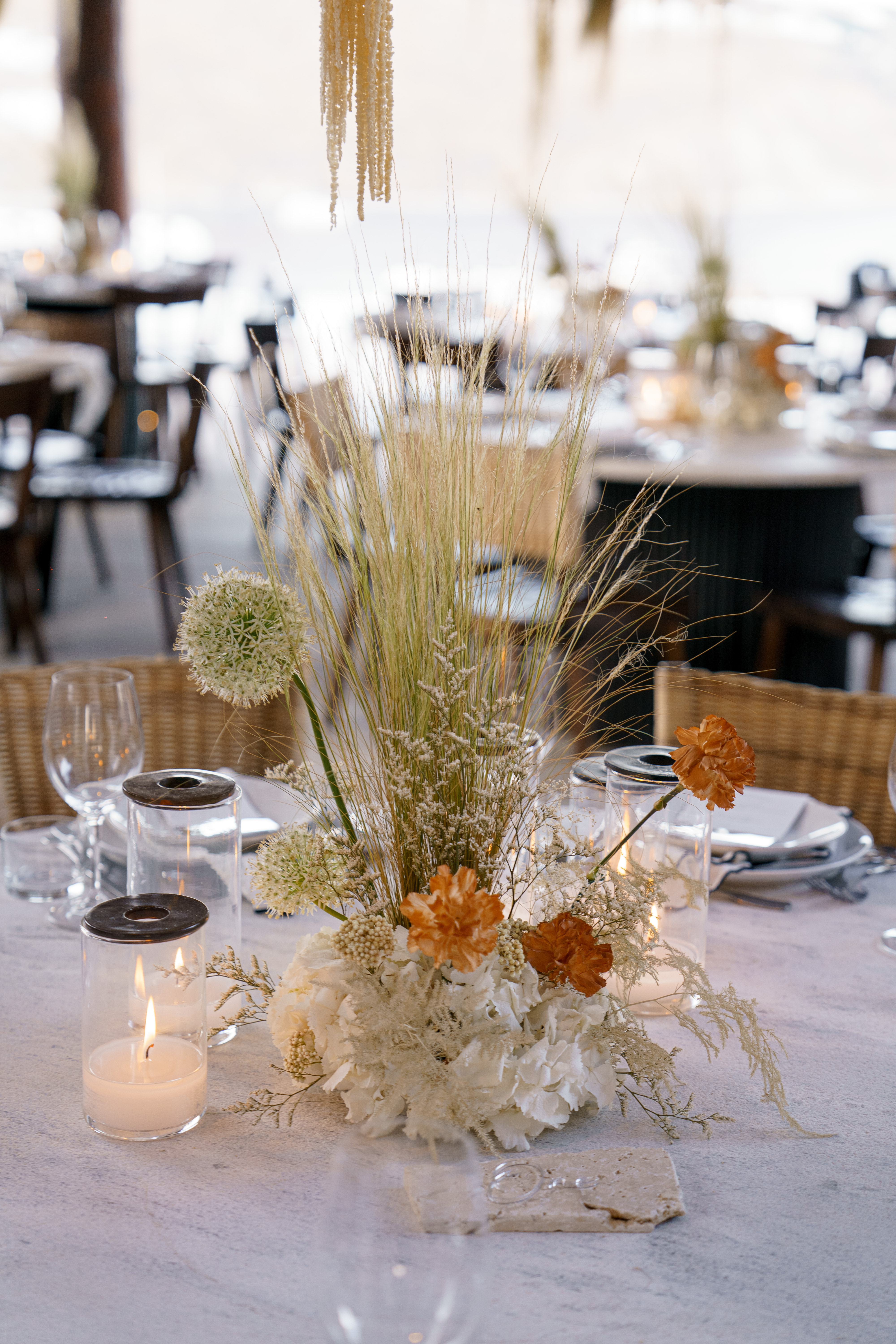 Elegant wedding table decoration with white hydrangeas, dried grass, orange flowers and candlelit