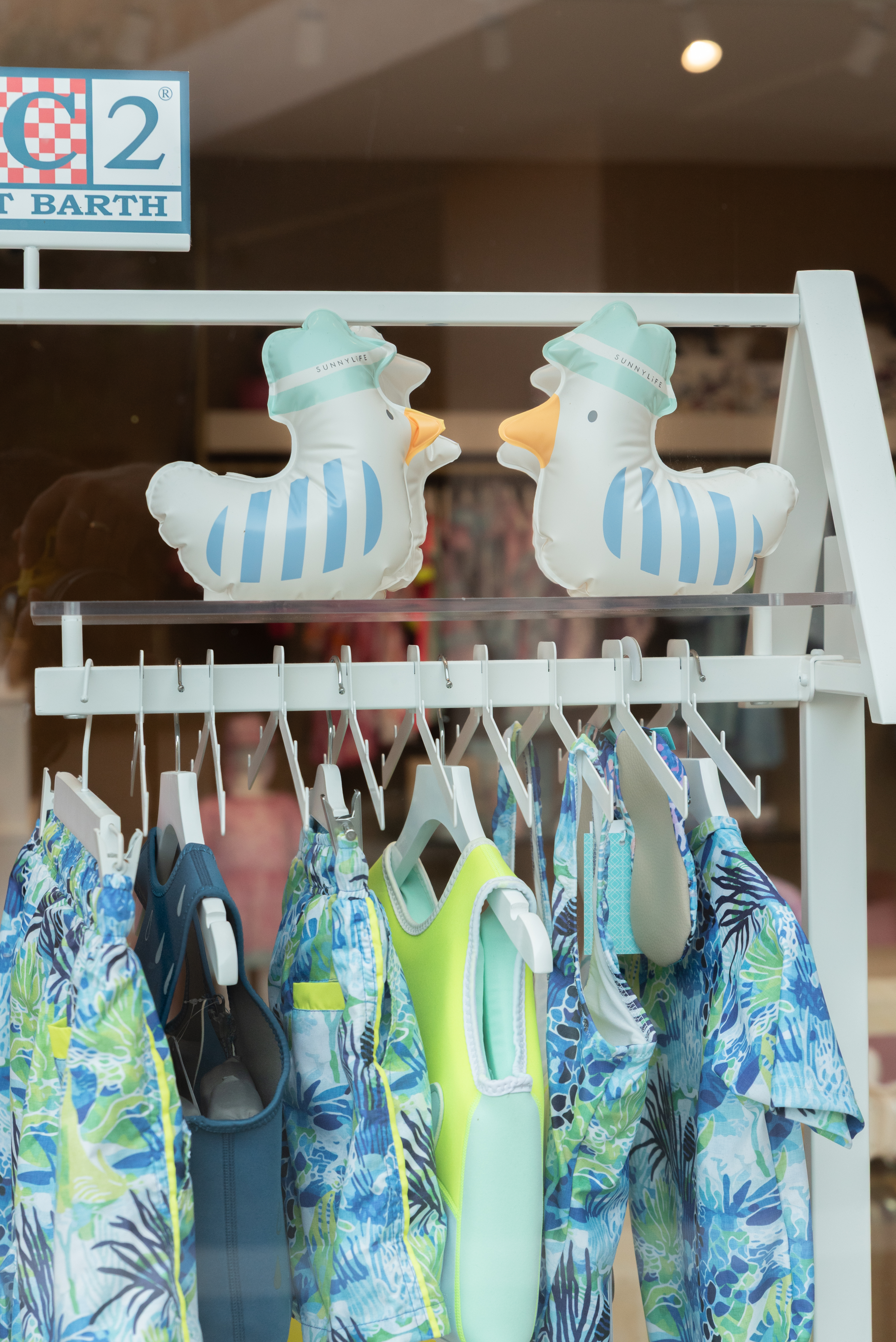 Colorful children's swimsuits in blue and neon yellow with two inflatable ducks wearing hats