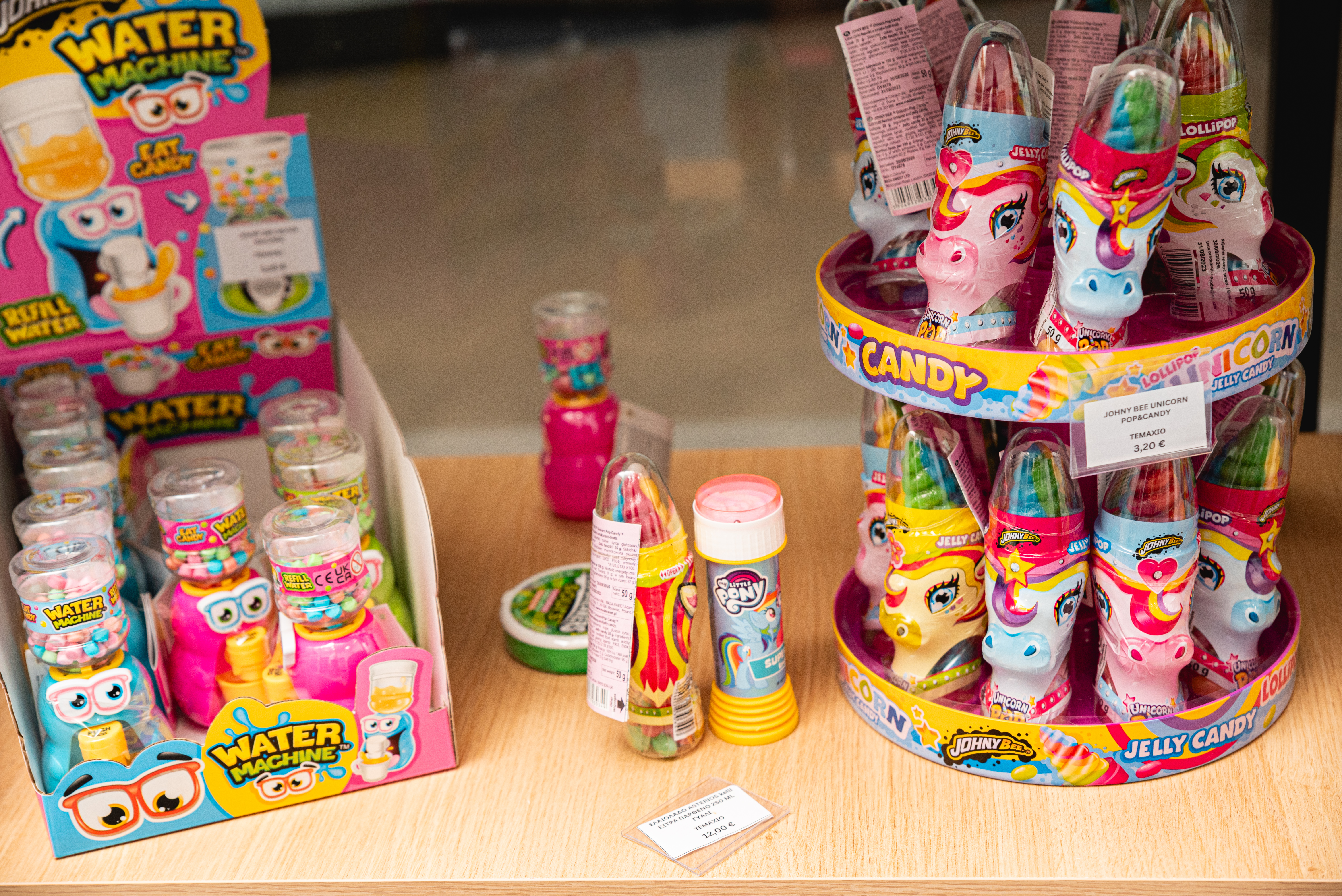 Colorful candy toys and unicorn shaped lollipops displayed on a wooden counter