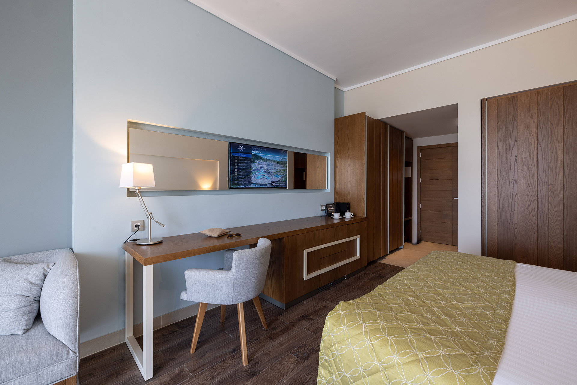 Deluxe sea view room interior with work desk, wooden furnishing, and wall-mounted smart TV