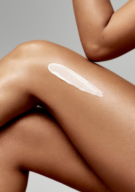 Close up of a person's leg with a smooth, even skin tone, showing a streak of white cream applied on the thigh