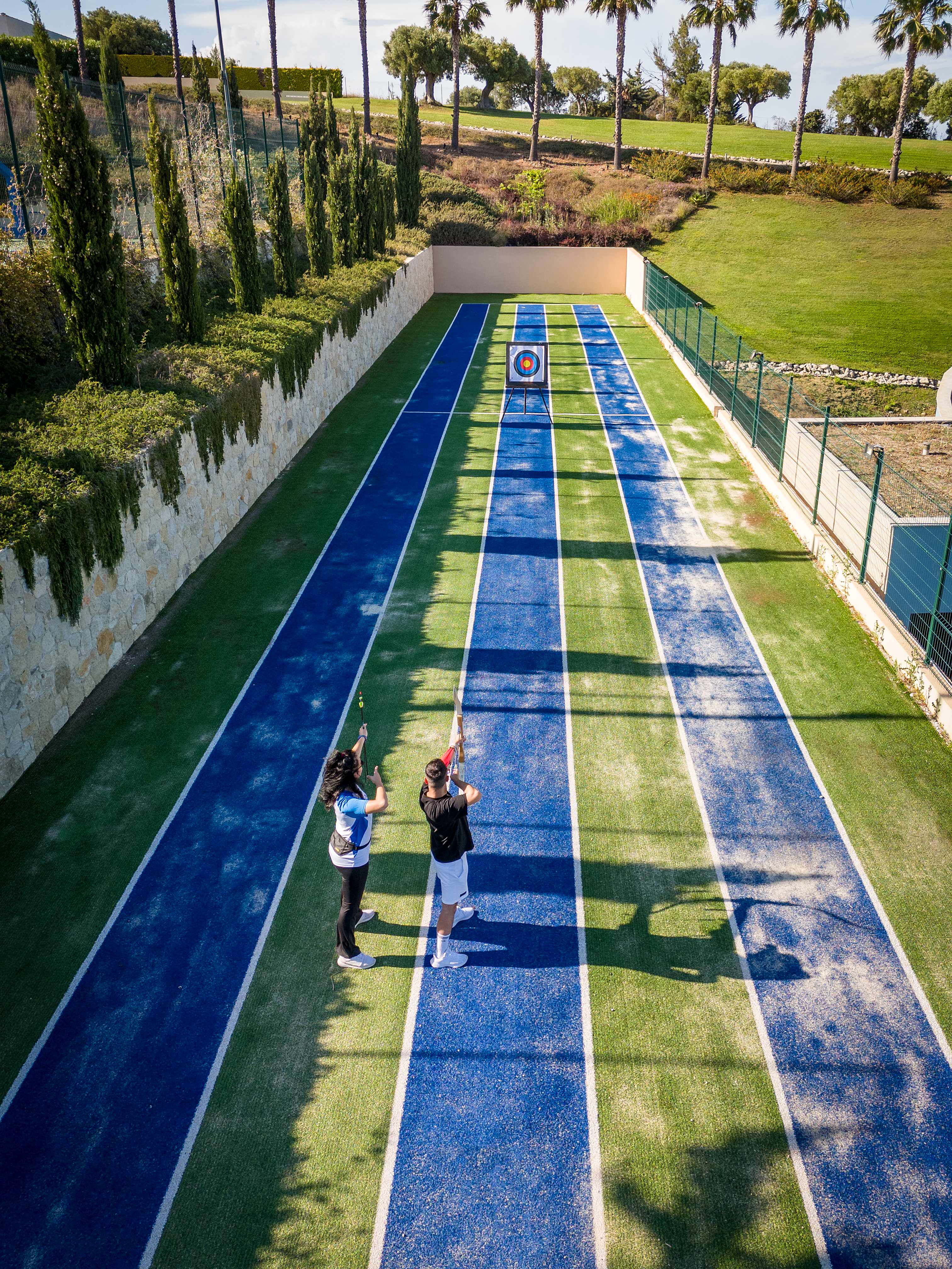 Archery field with two archers aiming at colorful targets under the sun