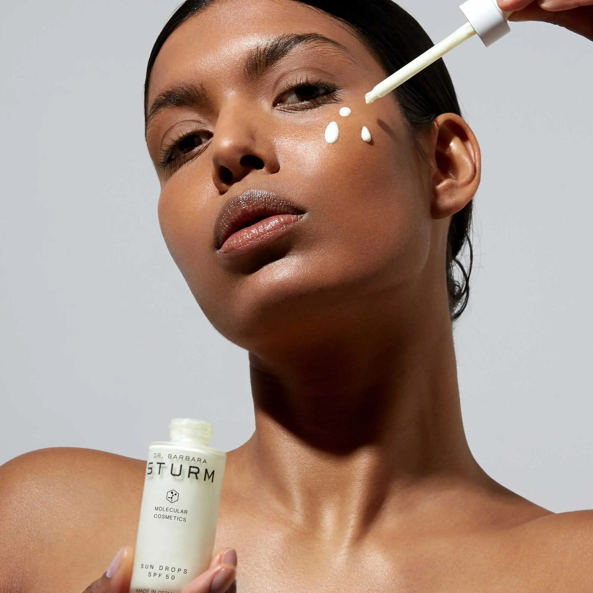 Applying Dr. Barbara Sturm sun drops SPF 50 for radiant, protected skin